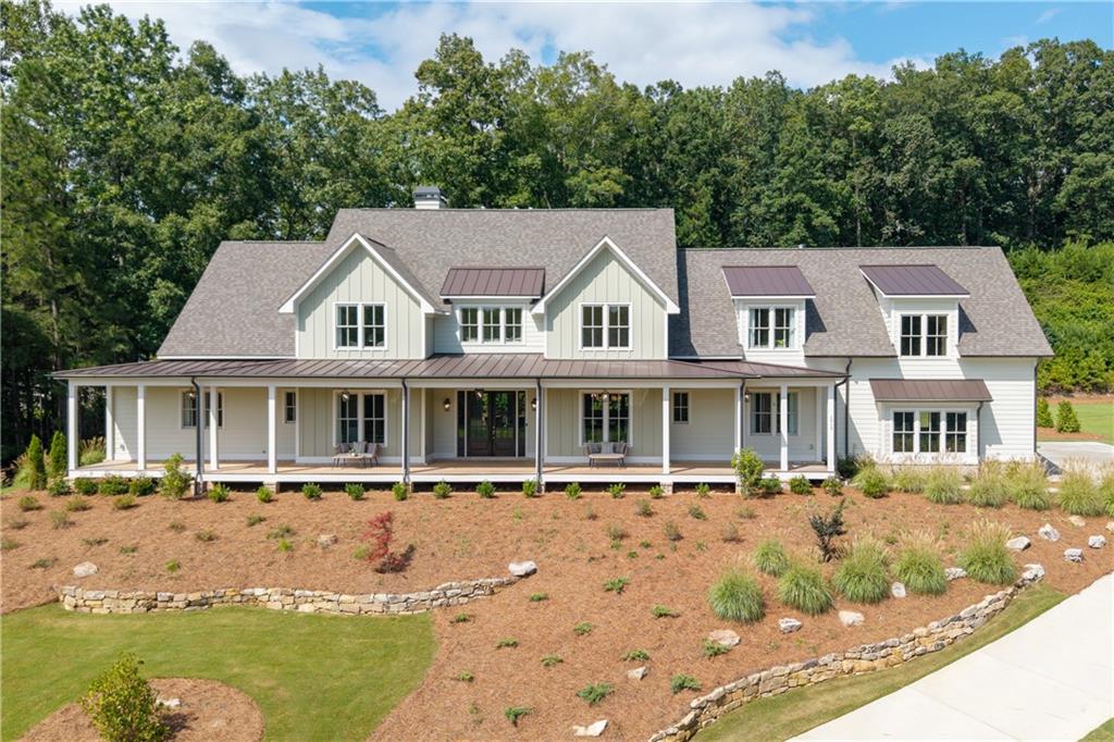 Ask about the Seller 5% buy down and preferred lender incentives. Elevated farmhouse – inspired living in Milton. This exquisite custom-built home in the Estate section of Crossroads, set on over an acre of manicured grounds, this home blends timeless elegance with modern luxury. A deep front porch frames sweeping treetop views, while 8-foot rear sliding doors open to a level backyard—ready for your dream pool and outdoor entertaining space. Inside, the open-concept design showcases a stunning chef’s kitchen with an oversized island, microwave drawer, dual sinks, and custom shelving. The 48" Thermador 6-burner range with grill is framed by white cabinetry reaching 10-foot ceilings and a custom Subzero enclosure. A fully equipped prep kitchen features an additional sink, dishwasher, ice maker, beverage refrigerator, and walk-in pantry. The main-level primary suite offers French doors to the backyard, three custom closets, and a spa-like bath with generous built-ins. A guest suite with a private bath completes the main floor. Upstairs, discover three additional bedrooms with en-suite baths, a spacious bonus room perfect for the ultimate media space , and an open mixed use space ideal for a game room, fitness area, or study. Private rear stairs from the garage drop zone and secondary entry lead to an expansive unfinished space, ready to be transformed post closing to suit your vision. Custom window treatments add the finishing touch to this meticulously designed home. Enjoy walkable access to dining, shopping and services, plus the benefit of award-winning schools—all in one of Milton’s most desirable locations.