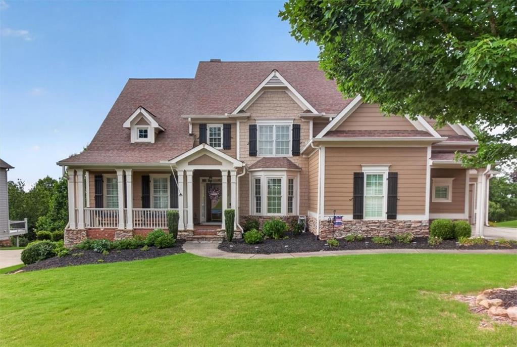 Two-story residential exterior featuring a prominent gabled roofline, mixed siding, and stone accents