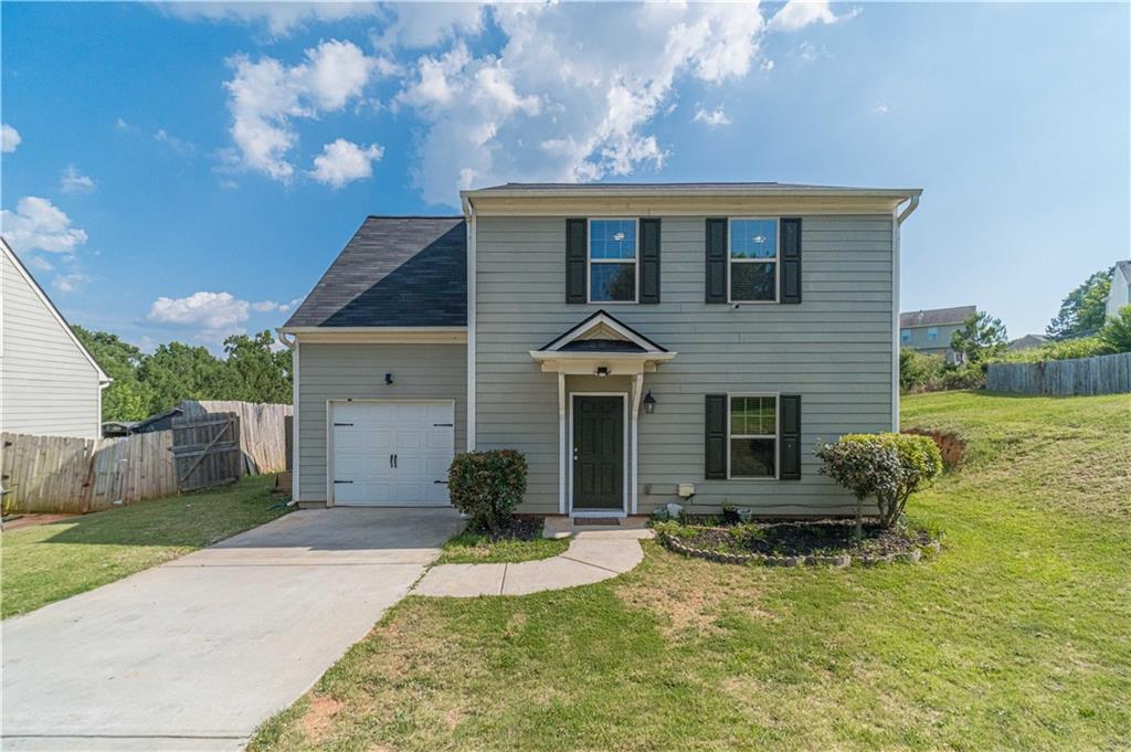 Two-story residence featuring siding exterior, a front entry garage, and a concrete driveway