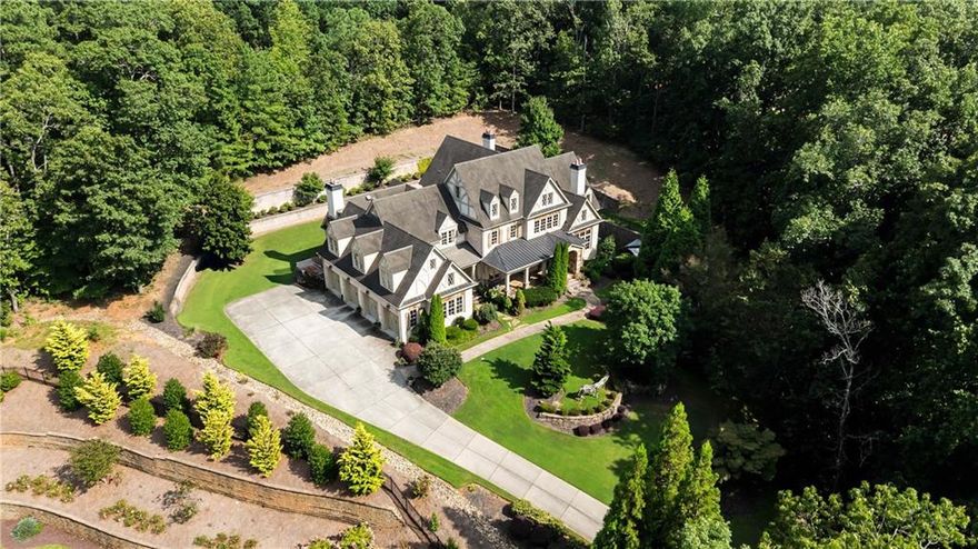 Nestled within the prestigious guard-gated enclave of Glenayre, this four-sides brick estate commands its hilltop setting with rare privacy, generous square footage, and seamless indoor/outdoor living. Behind the 24-hour manned gates, the residence unfolds with scale and sophistication: gracious proportions, soaring ceilings, and finely tailored architectural details including coffered ceilings, arched doorways, and extensive millwork. A dramatic two-story foyer sets the tone, leading into expansive living and entertaining areas designed for both formal gatherings and everyday comfort. Formal rooms include a vaulted, fireside paneled study, an elegant fireside living room, and a beautifully appointed dining room. The chef’s kitchen is a striking centerpiece with its oversized island, quartz countertops, Waterworks fixtures, and a suite of Wolf and Sub-Zero appliances. A butler’s pantry, mudroom, and adjacent fireside keeping room enhance functionality and flow. The main-level primary suite offers a private retreat, complete with a newly renovated spa bath featuring radiant heated floors and a steam shower. From the main level, doors open directly to a covered veranda and walk-out backyard, providing a natural extension of the home’s living and entertaining spaces. Upstairs, five ensuite bedrooms provide comfort and privacy, including a fully self-contained in-law or au pair suite complete with its own kitchen. A versatile loft and media room further enhance the functionality of the upper level. Smart-home technology ensures modern convenience throughout. The terrace level impresses with 14-foot ceilings and a wealth of amenities: a full bar, home theater, fitness center with dedicated bath and sauna, fireside family room, and an additional guest suite, all with direct access to the backyard for effortless entertaining. Minutes from Canton Street yet worlds away in privacy, this is one of Roswell’s most distinguished residential offerings, where craftsmanship, comfort, and security converge.