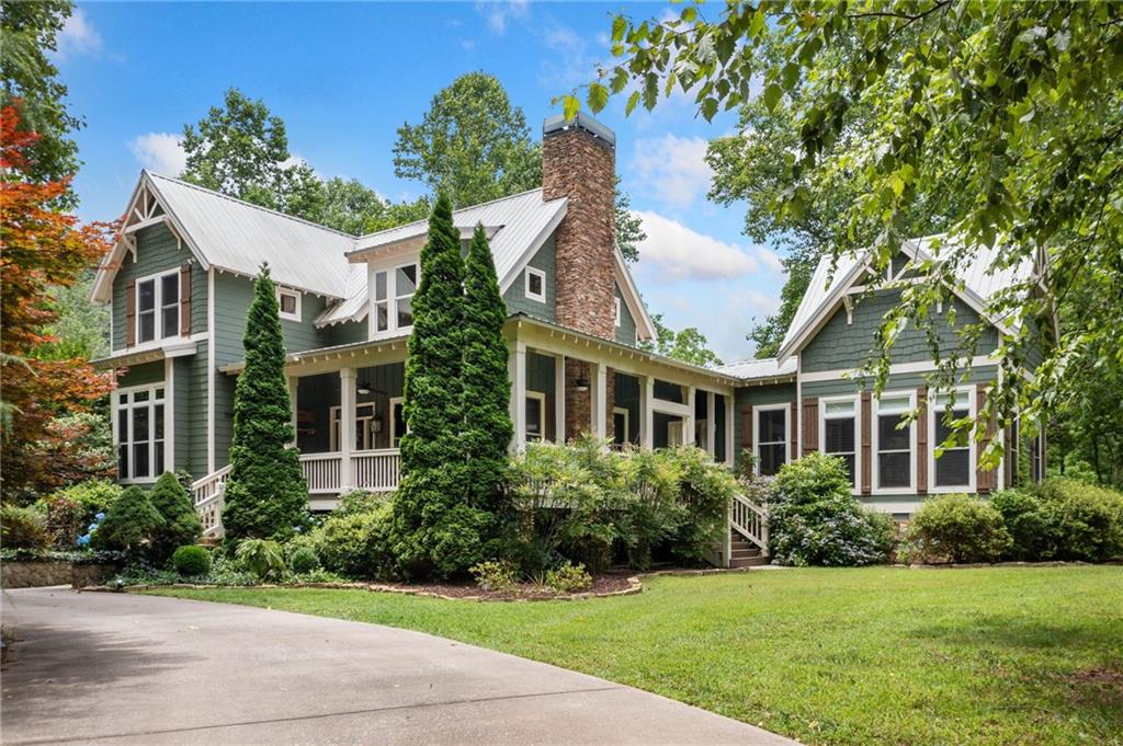 Once upon a time, in the land of the North Georgia mountains, there was an enchanting cottage surrounded by a laughing creek. This is IT, folks! Creekside Manor is THE storybook property. Located in the desirable Whitepath Road corridor—just north of downtown Ellijay and convenient to Blue Ridge—this Southern Living home is nestled on 3.31 acres, where Boardtown Creek and Jones Creek merge and meander around the property. The flat topography is nearly impossible to find up here! As soon as you enter the gate, you’re greeted by a long driveway bordered by a starter vineyard, fenced garden, SHE shed, and lush landscaping. Roll down the windows and listen to the babbling creeks as you approach the stunning Craftsman-style Westbury Park design home.
Step into the main level, where you’ll find a welcoming living room with a stacked-stone fireplace, a chef’s kitchen featuring a large granite island, brand new GE Café Collection appliances, a six-burner gas stove with double ovens, generous cabinetry, pantry, and more. The dining room is perfect for entertaining.
The primary suite on the main level has a private entrance, dual vanities, a soaking tub and shower, and his-and-hers closets. Adjacent to the kitchen is a cozy den/library with its own fireplace and ample built-in shelving. Upstairs are two additional bedrooms, a full bath, and a spacious gathering/sleeping room with beamed ceilings and a fireplace. Above the two-car garage, you’ll find a finished bonus room—ideal for a man cave, exercise room, or additional office space. The foundation/crawl space is engineered to withstand flooding. There is also a self-contained sewer/septic system. And don’t miss the grounds: over 1,200 feet of creek frontage, complete with a charming gazebo, creekside benches, a hammock, and a stone patio sitting area. From the wrap-around porches and from every room in the house, you have views to the creeks and the majestic mountains beyond. You won’t be disappointed when you explore this one-of-a-kind retreat. In fact, we can guarantee you will NOT want to leave!
The surrounding area is host to numerous wineries, apple houses, farmers markets, Whitepath Golf Course down the road, shopping and dining in downtown Ellijay and Blue Ridge, trout fishing, hiking, mountain biking, camping, kayaking and much more! Also enjoy nearby Carters Lake and Lake Blue Ridge and nearby Amicalola Falls Park or Fort Mountain Park for camping and hiking.