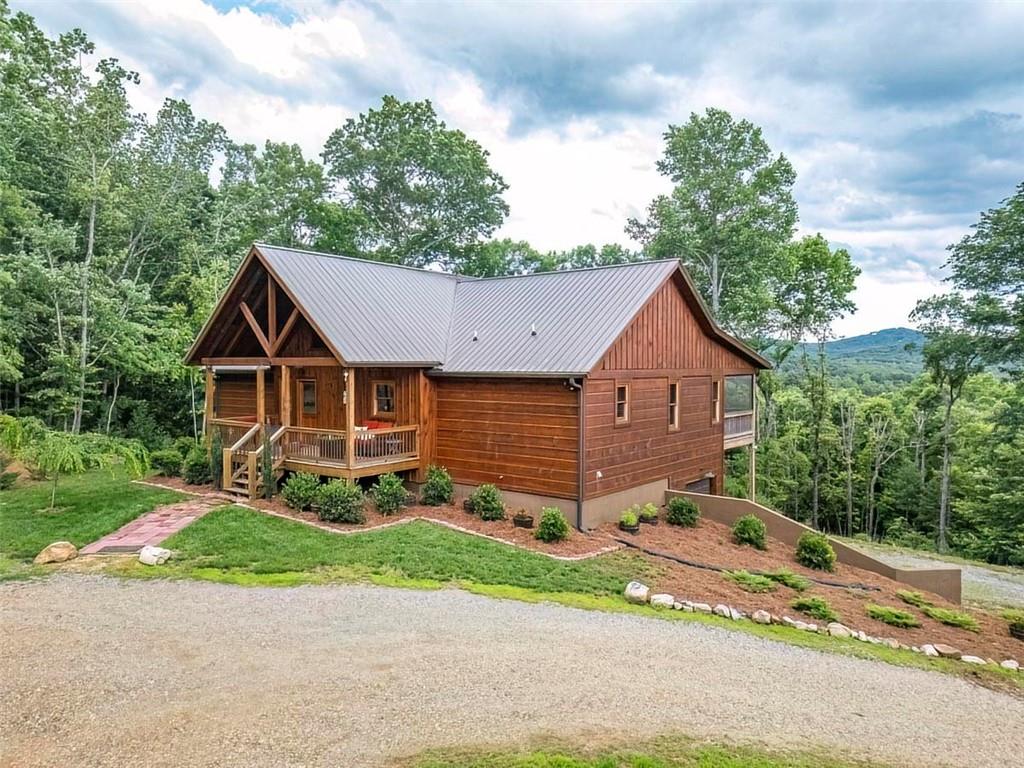 Escape to the tranquility and beauty of the North Georgia mountains in this stunning 2-bedroom, 2-bathroom home featuring a full basement with a garage that is stubbed, framed, and ready for additional living space and storage. Additional features include a dedicated pantry/laundry area with custom cabinets, a washer and dryer, and a laundry sink. Also, it includes a whole-house Generac generator and RV hookup equipped with electricity, water, and septic. The 3.11-acre property includes an additional lot, providing space for a detached garage or an extra home for investment or family expansion. Priced below the recent appraisal, this property is a must-see to appreciate all it has to offer. Experience spectacular sunset views in the North Georgia mountains—this home is waiting for you, as it is located on a quiet, wooded lot. This custom home is designed to capture breathtaking long-range and short-range mountain views year-round. It combines rustic charm with modern comfort, making it perfect for a full-time residence, vacation getaway, or investment rental. Enjoy high-speed internet access and easy proximity to hiking trails, wineries, and charming towns like Blue Ridge, Blairsville, Helen, Ellijay, and Murphy, NC. Step inside to an inviting open-concept living area with soaring cathedral ceilings and a cozy stacked stone fireplace. The well-appointed kitchen features granite countertops, custom cabinets, stainless steel appliances, and a breakfast bar that opens to the great room, perfect for entertaining or quiet nights. The spacious primary suite includes a private en-suite bath and direct access to one of the screened decks, where you can enjoy morning coffee or evening cocktails with panoramic mountain vistas as your backdrop. The second bedroom and full guest bath also provide ample space for family or guests, with direct access to their own private screened deck. Hit a HOME Run in the North Georgia Mountains!