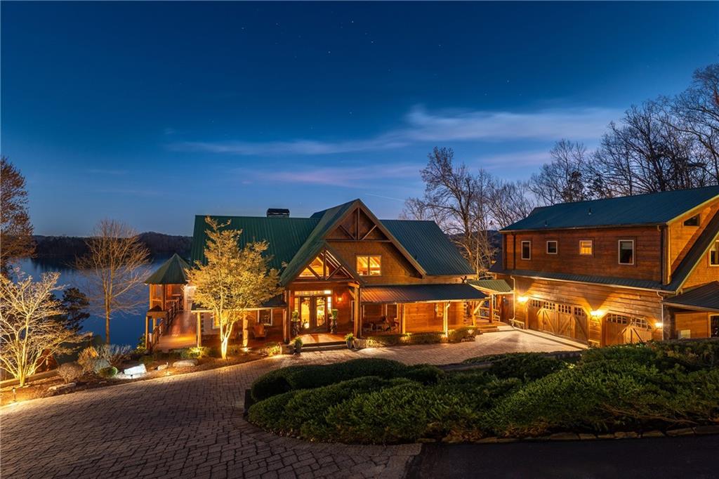 Welcome to tranquility within this 2+ acre, private & gated waterfront lake retreat! Enjoy year-round deep water on your 32x32 double slip dock & over 430’ of shoreline - situated next to large Army Corps-owned land parcel for ultimate privacy! NO HOA. Enjoy stunning 180-degree lake views from virtually every room and outdoor space of this property. Custom-built by Freddie Pethel and featuring luxury finishes, exceptional construction, artisan craftsmanship, towering windows, vaulted and beamed ceilings reaching 26 feet high, and an open concept design that evokes both warmth and sophistication. Enjoy plentiful outdoor spaces including expansive, multi-level decking, screened gazebo, outdoor kitchen and fireside/lakeside pavilion and plenty of room for a pool! Used the paved golf cart path or stone steps down to the lakeside pavillion for easy access. Owner's suite conveniently located on main level. Your guests will love the detached guest quarters complete with 2 beds and 2 baths, a full kitchen, living room & its own private balcony and views! The 32x32 covered dock with 2 slips (currently configured with 1 boat and 2 WaveRunner slips) is outfitted with extra-thick steel for wave protection, adjustable placement and a boat lift. One of the things that sets this magnificent property apart is the privacy provided by the plentiful acreage of adjacent untouched land owned by the Army Corp of Engineers. Designed with Colorado-inspired architecture, this spacious retreat blends natural elegance with modern technology, creating a seamless indoor-outdoor living experience. Let the Smart Home system work for you - set the lights, security sensors & cameras, private front gate entry, thermostats, and music throughout the home. Once inside, you are welcomed by beautiful Brazilian Cherry hardwood floors, and then immediately taken to the unobstructed lake views off the great room which hosts a professional masonry fireplace built by a local artisan; each stone hand-selected from 5 different U.S. States. Just off the entrance, you will find the owner's suite. The kitchen boasts custom cabinetry by William Ohs, gas cooktop, custom countertops, top-of-the-line appliances, and a large walk-in pantry. The mudroom and laundry room are located conveniently on the main level. Overlooking the great room is an upstairs loft that is currently an office, but could easily be utilized as a playroom or sleeping loft. Off the dining area is a rotunda keeping room with floor-to-ceiling windows and breathtaking views. Heading downstairs, either by the custom wood staircase or elevator, which services all levels of the home, you'll find a luxury terrace level retreat with soaring, 22' ceilings, floor-to-ceiling windows and even more lake views! This expansive space is perfect for entertaining and relaxation, offering a wine room, a full bar, and a billiard room for endless enjoyment. The elevator provides seamless access, while a flex room allows for versatile use—currently used for a sauna but could be used as a media room/theater or bunk room. Enjoy 365 lake views in the rotunda-shaped home gym and then relax in the steam shower! From all areas of the home, you can walk outside to enjoy the beauty of the lake. Walking out the terrace level is an expansive covered stone patio with easy access to the paved path down to the covered lakeside pavilion with fireplace right off the dock. This amazing property also features a waterfall, red cedar decking on three sides, ample parking - including space for boat or RV - and a workshop in the garage. Conveniently located to local favorite spots on the lake, including Gainesville and Port Royal Marinas, Pelican Pete's Bar and Grill, and Skogies restaurant. Close to downtown Gainesville, Chattahoochee Country Club, award-winning Northeast Georgia Medical Center, and Longstreet Clinic, and easy access to GA 400 & 1-985.