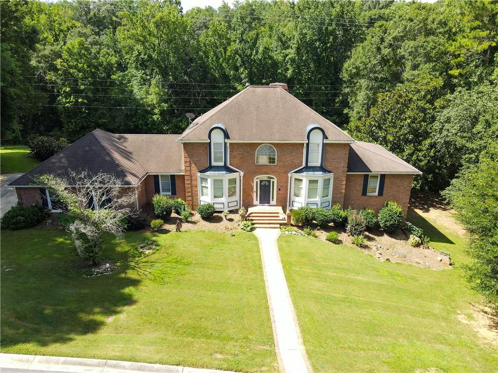 Lilburn Luxury Grand Estate on 2.43 Acres- A rare opportunity with No HOA in the Brookwood High School District! Welcome to your private retreat in the heart of Lilburn! This expansive 4BR, 3.5BA estate offers nearly 4,000 sq ft of living space-plus an unfinished basement with endless possibilities to add more square footage. Nestled on 2.43 pristine acres with a serene creek flowing just beyond the backyard, this home combines luxury, space, and tranquility like no other. Step inside the dramatic two-story foyer that opens into a spacious formal dining room that easily seats 12+, a flexible office or sitting room, and an inviting family room with fireplace. The updated kitchen is a chef's delight, complete with granite countertops and abundant cabinetry. On the main level you will find an oversized Laundry Room with incredible flexibility- previously used as a hair salon, this space offers excellent work-from-home or studio potential. Soak up the natural light in the enormous sunroom or step onto the oversized deck-perfect for relaxing or entertaining. This estate also features not one, but TWO oversized owner's suites-one on the main level and another upstairs. Upstairs also includes two additional large bedrooms and 2 full baths. The full unfinished basement is already stubbed for a bathroom and features a floor to ceiling brick fireplace, ready for your custom vision. With a 3-sided brick exterior, an oversized garage, and seller concessions for needed repairs, this home is packed with potential. Opportunities like this don't come often with acreage, luxury and room to grow!