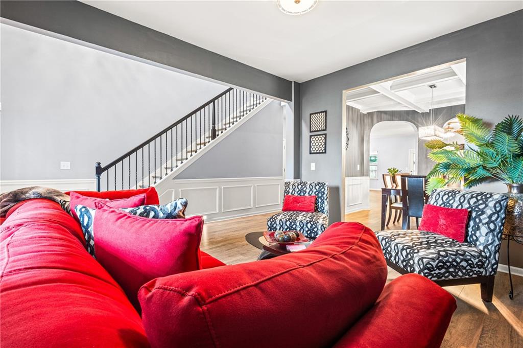 Interior living space featuring wood-finish flooring, a staircase with black iron balusters, and wainscoting
