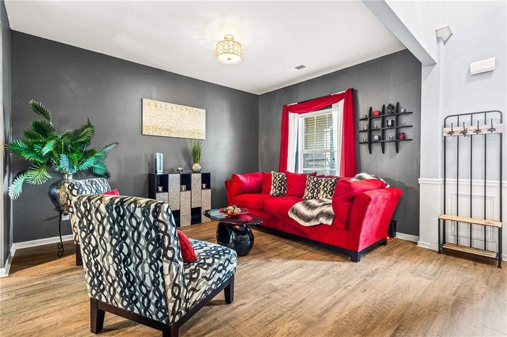 Living space featuring wood-finish flooring, dark accent wall, white ceiling, and a decorative ceiling light fixture