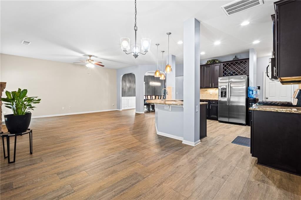 Coffered ceiling dining area featuring wood-finish flooring, wainscoting, and an arched entry