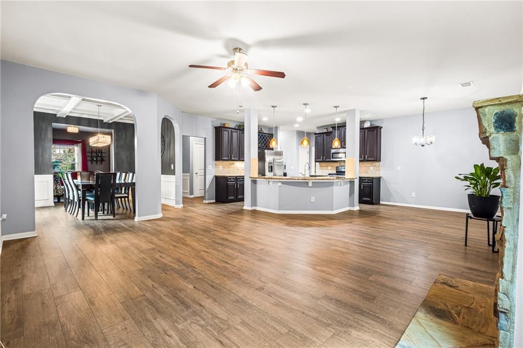 Interior living space featuring wood-finish flooring, a staircase with black iron balusters, and wainscoting