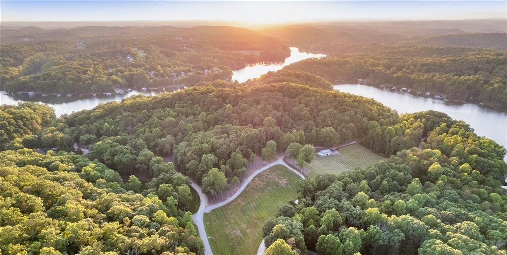 Welcome to your dream gentleman's ranch on the serene shores of the Northern End of Lake Lanier! An exceptional 40-acre property offering unparalleled privacy and endless possibilities, making it a truly unique find. This property includes Hall County-approved plans for a 14-lot vacation cottage subdivision, presenting a remarkable investment opportunity.  The centerpiece of the estate is a stunning 3,341 sq ft cabin, meticulously renovated in 2023. Step inside to discover an inviting and airy interior with expansive floor-to-ceiling windows that flood the space with natural light. The warm wood-paneled walls and ceilings complement the sleek, modern furnishings, creating a cozy yet sophisticated atmosphere. Upon entering the property, you'll find a beautifully renovated barn, equipped with power and water, making it ready for both livestock and chickens. The barn is enclosed in a ~3 acre fenced fescue pasture, offering ample space for horses or other animals. Adjacent to the fenced pasture is an additional 2.66 acre unfenced fescue pasture. Just on the other side of the fence and toward the lake is a naturally fed spring head! For those who love the outdoors, this property boasts a dedicated campsite with three tent pads and both water and power, perfect for family gatherings or weekend getaways under the stars. Explore the property on a hiking trail that winds throughout, offering stunning views of the mountains of North Georgia. The hiking trail is wide enough for full sized vehicles and side by sides. Additionally, a private shooting range away from the cabin and waterfront and abundant wildlife make this ranch a hunter's paradise. On the water, enjoy the brand new Martin Dock measuring 36'x26' with an 80' walkway that has been grandfathered in. The dock sits on 900' of pristine shoreline with 196' of rip rap and features two boat slips, an 8,000lb Hydro-Hoist lift, as well as ample seating and entertaining areas, making it perfect for enjoying long lake days with friends and family. A detached garage provides convenient storage for vehicles, boats, or recreational equipment, ensuring you have everything you need for lakeside living. Next to the garage is a 100' tall tower with business grade Starlink dish for high speed internet. Current internet is 300mb fiber from Spectrum for all of your streaming and work from home needs. Water on the property is provided by a newly overhauled well system. Yard hydrants are located at the steps to the dock, next to the garage, 3 in the pasture, and 1 at the camp site. Conveniently located just 6 miles from the North Georgia Premium Outlets, 30 miles from Alpharetta, and 67 miles from Hartsfield Jackson Atlanta International Airport via GA-400, and only 13 miles from downtown Gainesville, this property allows you to enjoy the peaceful seclusion of your own private wilderness while still being close to essential amenities. Whether you're seeking a peaceful retreat, a working ranch, or an investment opportunity, this gentleman's ranch on the Northern End of Lake Lanier has it all!  Develop immediately, hold for future potential, or create a private retreat with family and friends, the possibilities are almost limitless!