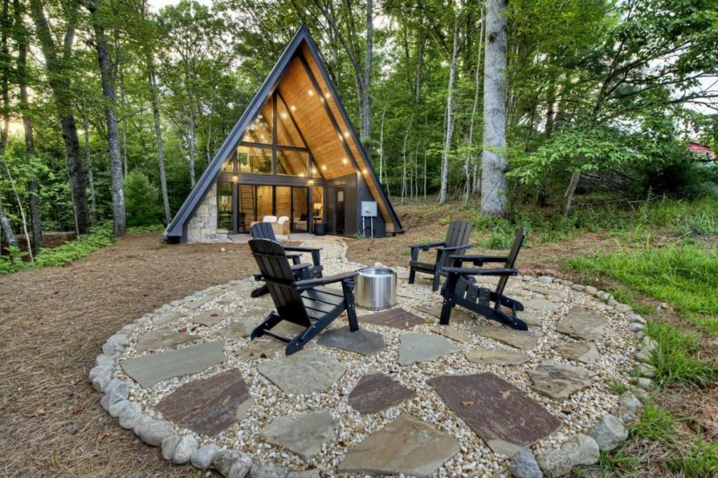 Tucked away in a serene, private setting just minutes from Downtown Blue Ridge, this striking modern-rustic A-frame offers an unparalleled mountain lifestyle. Framed by a lush rolling meadow and accented by soft short-range mountain views, this architectural gem is the epitome of luxury mountain living. Soaring floor-to-ceiling glass walls invite the outdoors in, filling the open-concept living space with natural light and showcasing the beauty of the surrounding landscape. The great room features a seamless flow between the living area, dining space, and a fully equipped kitchen-perfect for entertaining or unwinding fireside after a day of adventure. With one bedroom and a full bath on the main level, and a second picturesque bedroom loft above, the home is fully furnished and turnkey-ready-ideal for a high-performing short-term rental or a private mountain escape. Step out onto the covered back porch with a gas fireplace for cozy evenings under the stars, or follow the charming pebbled path to your own fire pit nestled in nature's embrace. Home is wired and ready for a hot tub. For the visionary, there is room on the property for a garage, guest house, or additional dwelling to complement the creation completed new. Find yourself immersed in the stars while positioned in your own private North Georgia meadow. A rare offering at an exceptional value, this A-frame retreat is your gateway to the tranquil luxury of North Georgia mountain living. **Rental estimates of $60-70k annually.** Inquire for more information!