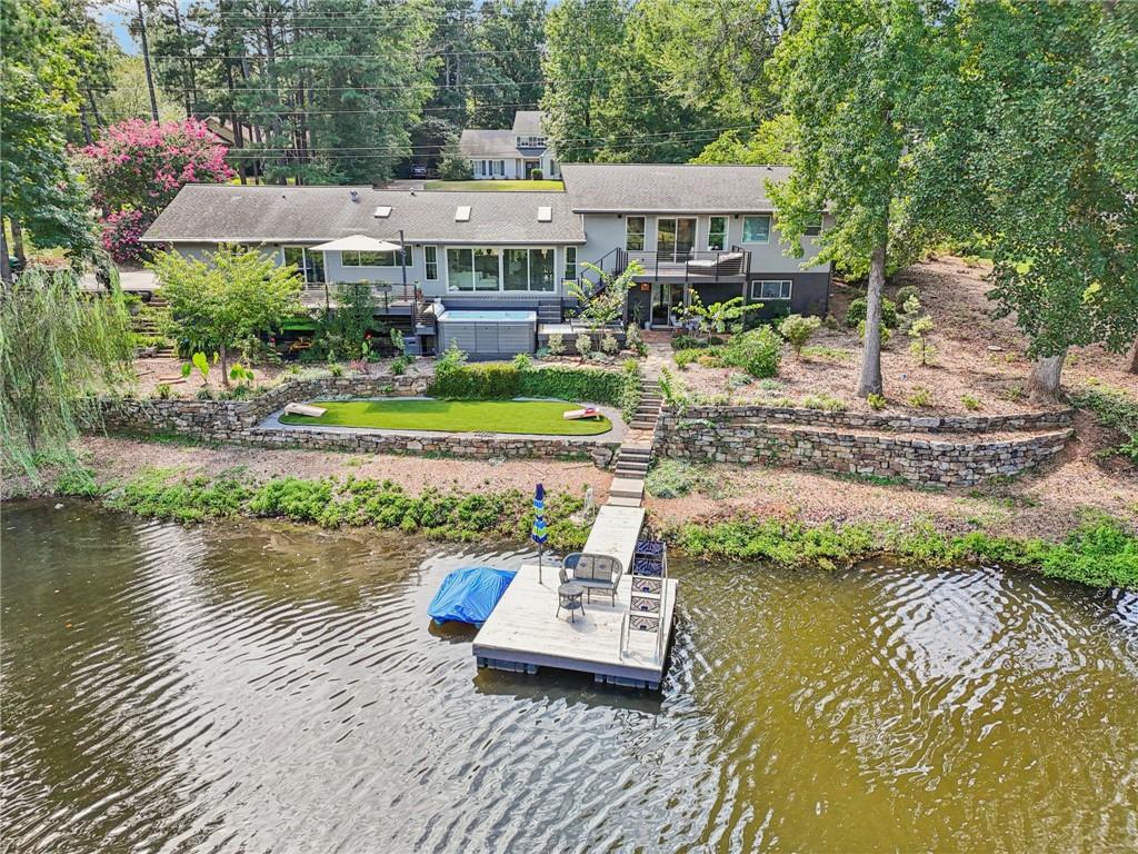 Lake life reimagined in the heart of West Roswell! Gorgeous Private Lakefront Living on Nearly 2 Acres a hop, skip and a jump to Historic downtown Roswell. Beautifully modernized home with sweeping front yard, new landscaping, and stone accents. Inside, the formal dining room offers built-in bookshelves, while a versatile flex space is perfect for a home office, reading nook, or formal living. The bright, open-concept living room boasts a wall of windows with panoramic lake views, fireplace, skylights, and built-ins. The modern kitchen shines with European-style cabinets, KitchenAid stainless steel appliances (including double ovens and 42" built-in fridge), Thermador induction cooktop, oversized island with seating, wine fridge (dual cooled for both white and red wines), coffee bar, and walk-in pantry. Wake up to lake views in the primary suite with private deck access, dual walk-in closets, and a spa-like en-suite with quartz counters, dual sinks, and a large fully tiled frameless glass shower. Two spacious secondary bedrooms share a full bath. The finished lower level features a huge game room with wet bar, full bath, and laundry, all with walk-out patio access. Step outside to your dreamy backyard retreat with two decks, outdoor kitchen w/ Blaze outdoor built-in gas grill w/ SS storage and quartzite top, hot tub, covered patio, fire pit, green space, lake access, and private dock w/ power and water! Upgrades include: new dock floats and cedar decking, sprinkler system and landscaping, new main water line, Hardi plank siding with fresh paint, 220 outlet in garage for EV charging, filtered water, and tankless water heater. Don't miss your opportunity at an unmatched lifestyle: West Roswell address, lakeside retreat!