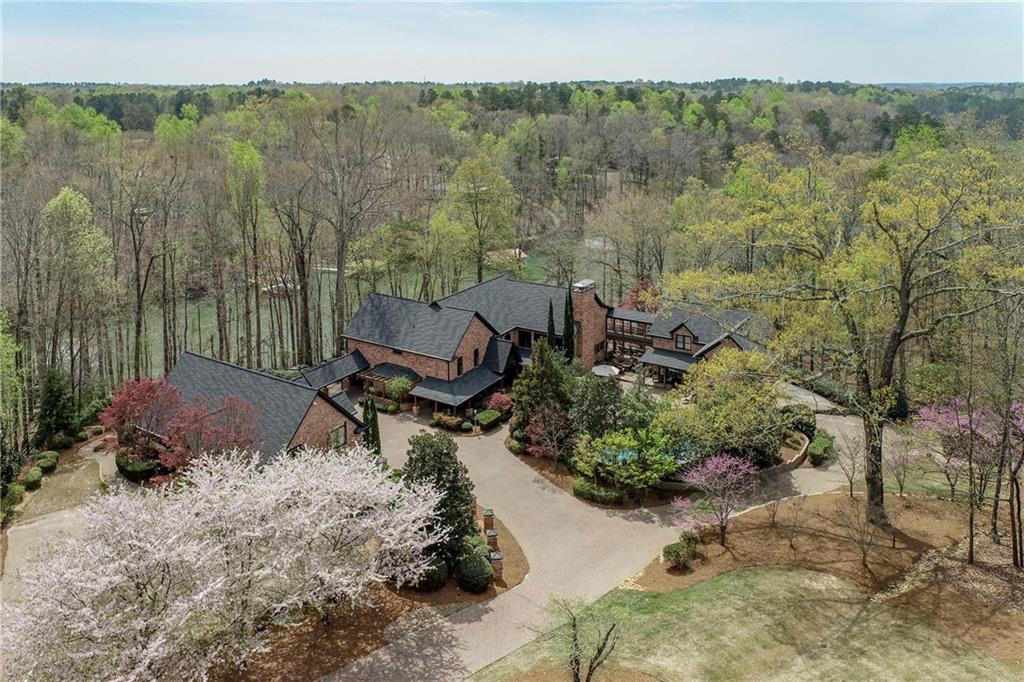 Extraordinary 3-building complex on Lake Lanier w/ magazine-quality finishes & dream amenities. Could easily house multiple groups in lavish luxury. This lakefront showcase includes a decorator's masterpiece main home, separate guest house & pool house/gym that could be a 3rd residence. Other important features: double slip party dock on deep water, short walk to lake & beautiful views, drivable road to dock, heated saline pool w/ rock waterfall, 2 garages for 7 large bays, RV parking, gated entrance, open floor plan, gorgeous bar & the owners' suite is to-die-for. Too many architectural features to mention, but here are some highlights. Stunning coffered ceilings, grand stone fireplaces in family room & master, massive bar room w/ billiards & media sections, decks & patios to accommodate an army (almost), 33,000 sq. ft. of pavers on the driveway & patios, one-of-a-kind entry gate, pro appliances in main house & guest house, gorgeous landscaping including lighted trees on timers for whimsical effect. Huge 4.32 acre lot maximizes privacy while providing room to grow, if needed. You will NEVER find another property like this one, guaranteed. Virtual showings available upon request.