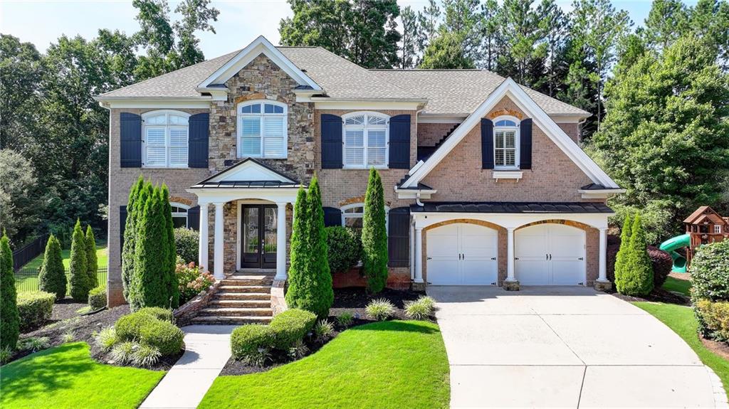 View of front facade with driveway, brick siding, a front lawn, and stone siding