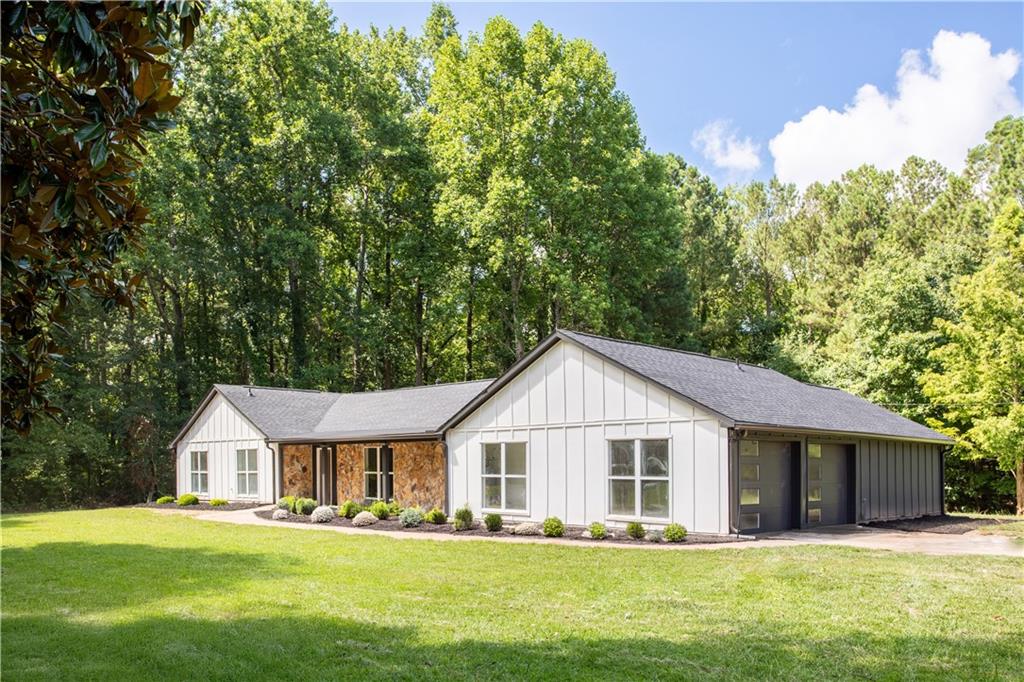 Discover the perfect blend of charm, privacy, and modern upgrades in this beautifully renovated 4-bedroom, 3-bathroom farmhouse-style ranch, complete with a bonus room ideal for a home office or flex space. Set on 1.5 private acres in Austell, this property offers no HOA and no Mableton city property taxes—delivering both lifestyle freedom and long-term savings. No detail was overlooked in the full renovation, which includes a new roof, house wrap, exterior siding, fascia, soffits, and garage door. Inside, the home features all-new sheetrock walls and ceilings, solid interior doors, high-efficiency insulation (R38 ceiling / R19 walls), and luxury flooring throughout. The heart of the home is a stunning, fully updated kitchen with shaker cabinetry, quartz countertops, and brand-new stainless steel appliances, opening to a light-filled living area anchored by a sleek electric fireplace and modern lighting. All three bathrooms have been tastefully remodeled with contemporary finishes and clean lines. Additional upgrades include a new HVAC system, smart thermostat, updated electric fixtures, and a new water heater. Outside, a freshly poured concrete patio offers the perfect setting for entertaining or relaxing in your expansive backyard. Stylish, functional, and completely move-in ready—this is the turnkey opportunity you've been waiting for. Landscaping photos are virtually enhanced.