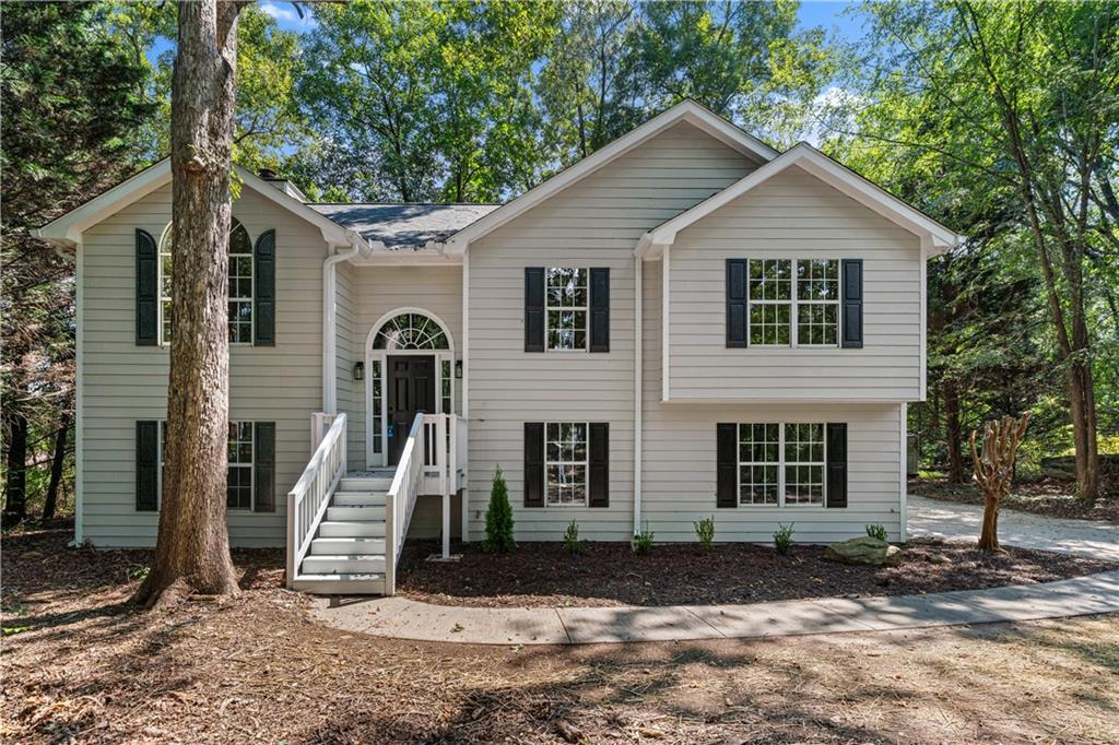 R.E.N.O.V.A.T.E.D. All the polish of new construction BUT without the postage stamp lot or HOA rules. Set on a wooded acre in the NEW Heroes Elementary School District, this BETTER THAN NEW CONSTRUCTION where a modern refreshed home delivers a spacious layout, long driveway, mature privacy, and on trend finishes. Luxury laminate flooring carries seamlessly through the main living areas, while the bedrooms offer newly laid, soft-to-the-touch carpet for cozy comfort. The heart of the home, the kitchen has been totally reimagined with soaring ceiling height new cabinetry, Corian countertops, a baked scone tile backsplash, and a full suite of stainless appliances. Every bathroom was gutted and rebuilt in a serene, spa-like style featuring marble looking tiled floors, brand new vanities, new mirrors, tiled tub surrounds, and new toilets. The owner's suite bath is the ultimate glow up, starring a show stopping (or shall we say shower stopping) deep, freestanding soaking tub-your personal retreat at the end of the day. A layout that truly adapts to all the needs - Enjoy 3 bedrooms/2 baths on the main level plus 2 additional bedrooms and a full bath on the lower level-perfect for multigenerational living, extended stay guests, or dedicated spaces for work, fitness, and play. Both levels open to their own outdoor decks, inviting you to spread out and savor the green, serene setting you won't find in most new construction.