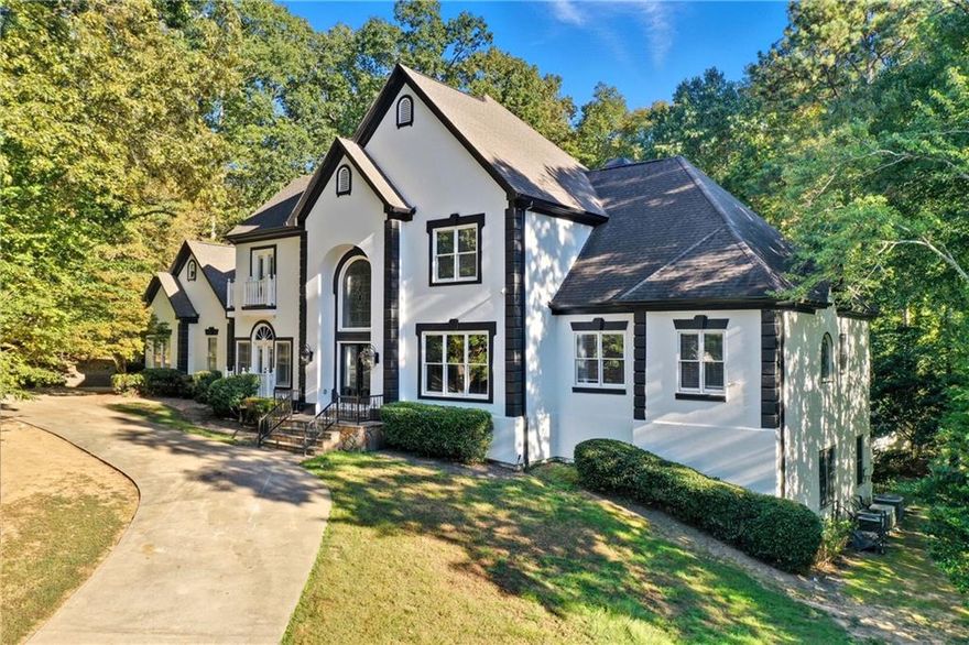 Stunning European-inspired estate in prestigious Guilford Forest Estates! Over 10,000+/- sq. ft. of luxury living on a private 1.11+/- acre lot. Grand foyer with sweeping staircase opens to a sunlit great room with soaring arched windows. Gourmet kitchen features granite countertops, copper accents, six-burner gas range, and double ovens. Main-level owner’s suite offers a fireplace, sitting room, and renovated marble spa bath. Terrace level includes theater, game room, gym, wine cellar (or 7th bedroom), two additional bedrooms, two full baths, and second kitchen with walkout to pool. Features include 3-car garage with EV outlet, fenced yard with irrigation, and central vacuum. Minutes to I-285, shopping, dining, and airport.