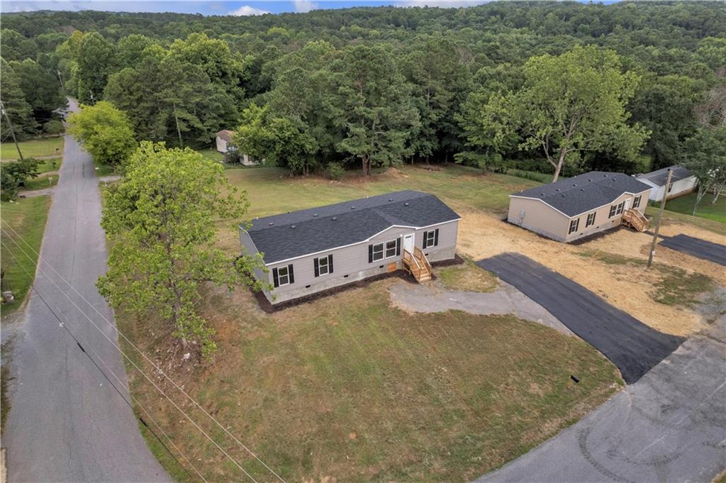 Move-In Ready Double Wide on Spacious Lot! Within 2 miles of Lake Allatoona! Welcome home to this brand new, never-lived-in double wide manufactured home situated on a generous corner lot in a peaceful rural setting. Featuring an inviting front porch and a rear entry with new wood decking, this home offers both curb appeal and functionality. Inside, you’ll find a bright, open floor plan with stylish, low-maintenance LVP flooring throughout the main living areas. The spacious living room flows seamlessly into a modern kitchen complete with an oversized island, abundant cabinet space, durable countertops, and black appliances including stove, refrigerator, and dishwasher. Adjacent to the kitchen is a designated dining area with large windows for natural light. The split-bedroom layout provides privacy with a large primary suite featuring a walk-in closet and large private bath. The en suite bath includes a spacious vanity, tub/shower combo, and modern finishes. Two additional bedrooms (both with walk-in closets) share a second full bathroom, perfect for guests or family. A dedicated laundry/mudroom with exterior access adds convenience and functionality. Outside, enjoy a large, open lot with plenty of room for a garden, play area, or future outbuildings. Paved parking and fresh grass and mulch give this property a clean, finished look. New HVAC and septic tank! If you're searching for affordable, move-in ready living in a serene location, this home is ready to welcome you.