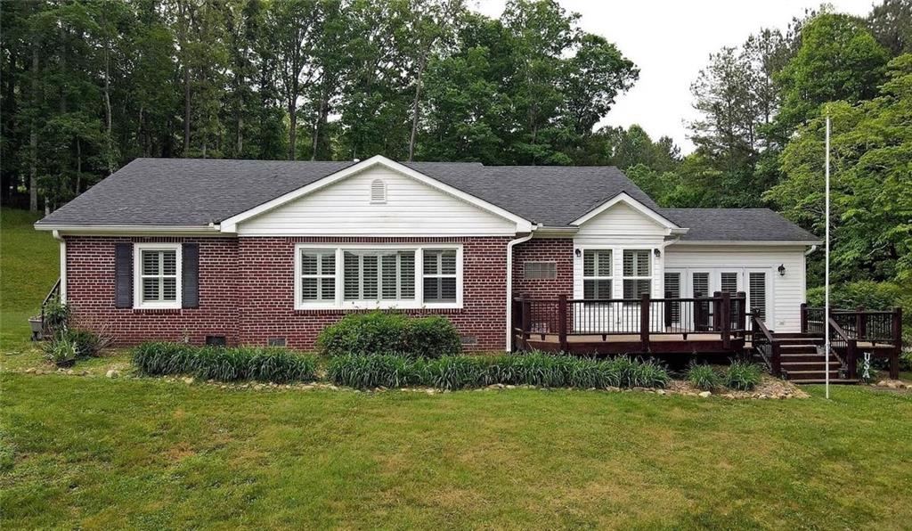 Timeless traditional brick meets modern convenience in this beautifully updated North Georgia mountain retreat. Originally built in the 1950s, this spacious 3-bedroom, 2-bath home has been thoughtfully renovated for today's lifestyle. Subtle color palettes flow throughout, complemented by natural light filtering through plantation shuttered windows. The kitchen boasts granite countertops, custom cabinetry, and a seamless transition to the separate dining room and cozy fireplace-ideal for family gatherings. A large living room with its own fireplace features wall-to-wall windows that capture stunning country vistas. The grand master suite is a true retreat, complete with a luxurious tile bathroom and heated floors. Step outside to your dream workspace: a detached 3-bay garage, fully equipped with HVAC, a bathroom featuring a tankless water heater, and a built-in compressed air line for pneumatic tools. The garage features extra-tall ceilings for accommodating larger projects, a smart MyQ garage door opener, and convenient pull-down attic stairs for added storage. Whether you're a car enthusiast, craftsman, or simply need extra space, this garage delivers unmatched versatility.