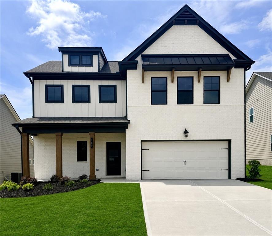 Contemporary two-story residence featuring a white brick and vertical siding exterior, black-framed windows, an attached two-car garage, covered entry with wood-finish columns, and a well-maintained lawn