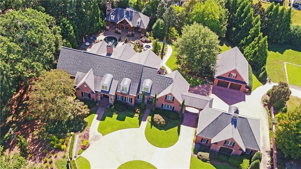 Imagine coming home to this extraordinary brick and stone custom estate with unparalleled privacy! Double iron gates welcome you into this well manicured 5.76 acre paradise. A circular drive and porte cochere lead to two garages with room for 5.5 vehicles along with a large parking pad. Both have finished, heated and cooled rooms above with one being an office and the other an exercise room. Amenities include a saltwater heated pool and spa, pool house with kitchen and fireside seating area, full bath and washer and dryer in the storage room. A deep well services the commercial irrigation system and the home has a whole house humidifier, dehumidifier and fresh air system. Double iron castle doors lead into the grand two story foyer flanked by the formal dining room on the right and a study / library on the left. Located on the main level, the primary suite offers a spacious spa like bath, an amazing spacious custom closet with a great view of your private pool paradise. The grand room with a floor to ceiling stacked stone fireplace accentuates the 24+ foot coffered ceiling with windows overlooking the amazing outdoor living space and pool. The well appointed chef’s kitchen with commercial grade appliances includes a Wolf gas cooktop, Sub Zero refrigerator and freezer, Miele coffee bar, warming drawer, ice maker, dishwasher, vegetable sink, workstation and a large custom walk-in pantry. The upper level consists of three en suites all with custom walk-in closets and a bonus room with great storage space. Entering the terrace level you will walk into a game room with a large brick fireplace, bar area which has a Sub Zero refrigerator, wine cooler and wet sink, a wine cellar, half bath and gym. The theater room seats eight and the 130 inch screen and electronics will convey. On to the summer kitchen which opens to the dining area and family room. Everything you need for entertaining at the pool with another Sub Zero refrigerator, six burner gas cooktop, warming drawer, microwave, dishwasher, ice maker and double sinks. A spacious bedroom with a full bath and custom walk-in closet completes the terrace level. As beautiful as the interior space is, you will also be amazed at the resort-like backyard featuring a covered lower patio, spa, salt water heated pool with water features and a bridge leading to the pool house. Great entertaining space with a stone fireplace and T.V. lounging area, a 60 inch grill, refrigerator, wet bar and a storage room which has a washer and dryer to conveniently wash your pool towels. The pool bath has a tile floor and shower. This majestic estate offers the best of both worlds as it is very private yet conveniently located close to area restaurants, the Northeast Georgia Medical Center offices and hospital, Chateau Elan Winery and Resort and I-85. Call with questions or to schedule your private showing.