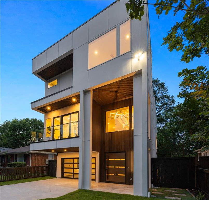 There is modern—and then there is modern reimagined. Perfectly positioned in Atlanta’s highly sought-after Ormewood Park, 1102 Sanders Avenue is a striking new construction blending bold architecture with a stellar intown location just blocks from the BeltLine, East Atlanta Village, and the emerging Memorial Corridor.
Beyond the gated drive, a dramatic 6-foot pivot door opens into soaring interiors where 30-foot ceilings frame the home’s defining centerpiece—a sculptural floating staircase with glass railings, illuminated by a cascading two-story chandelier. Pella windows and doors flood the interiors with natural light and create seamless indoor-outdoor connectivity across multiple terraces and decks. Wide-plank white oak flooring flows throughout, setting a warm, sophisticated tone.
The facade features concrete fiber cement panels, composite slat wood accents, and glass rail systems—a refined, durable, low-maintenance material blend that elevates curb appeal and ensures long-term ease of ownership.
Inside, the open living room centers around a floor-to-ceiling linear gas fireplace wrapped in large-format porcelain slabs for a showstopping statement. Adjacent, a dedicated office/den offers flexible space for work or relaxation while maintaining open sightlines to the living areas.
The designer kitchen makes a bold statement with a waterfall-edged quartz island and custom cabinetry. Dramatic quartz continues up the full-height backsplash wall, elegantly framing a large picture window. A walk-in pantry with butcher block counters adds prep space, while the premium appliance suite includes a sleek induction cooktop, paneled counter-depth refrigerator, and paneled dishwasher blending seamlessly into the cabinetry. Oversized sliding doors extend entertaining space to a deep covered deck overlooking the private backyard with room for a future pool. A powder room with full-height tile, floating vanity, and integrated sink delivers elevated design.
Rare for modern construction, the main level also includes a fully self-contained in-law suite with its own kitchen, living room, bedroom, bath, and private exterior entrance—ideal for multigenerational living, extended guests, or income-producing potential.
Upstairs, the private owner’s suite opens to its own covered balcony with treetop views. The spa-inspired bath features backlit mirrors, floating dual vanities, oversized wet room with freestanding tub, and a luxurious multi-head shower system. Dual boutique-style walk-in closets complete the retreat. Two additional bedrooms, full bath, and a fully outfitted laundry room with custom cabinetry, sink, and folding counter complete the upper level.
Multiple outdoor living spaces—including the rear deck, primary suite balcony, and a front terrace off the upstairs den—invite effortless indoor-outdoor living year-round. The fenced backyard centers around a majestic oak tree, while a built-in fire pit creates an inviting gathering space. The side yard features artificial turf and stone pathways for low-maintenance enjoyment.
Designed for today’s lifestyle, the home also features a 2-car garage with glass + metal door, private gated drive, and secure off-street parking—a rare amenity in this highly walkable intown setting.
All of this, just moments from Atlanta’s most vibrant shops, restaurants, breweries, parks, and trails—1102 Sanders Avenue delivers cutting-edge design, highly functional living, and the ultimate intown lifestyle in one of Atlanta’s most dynamic historic neighborhoods.
