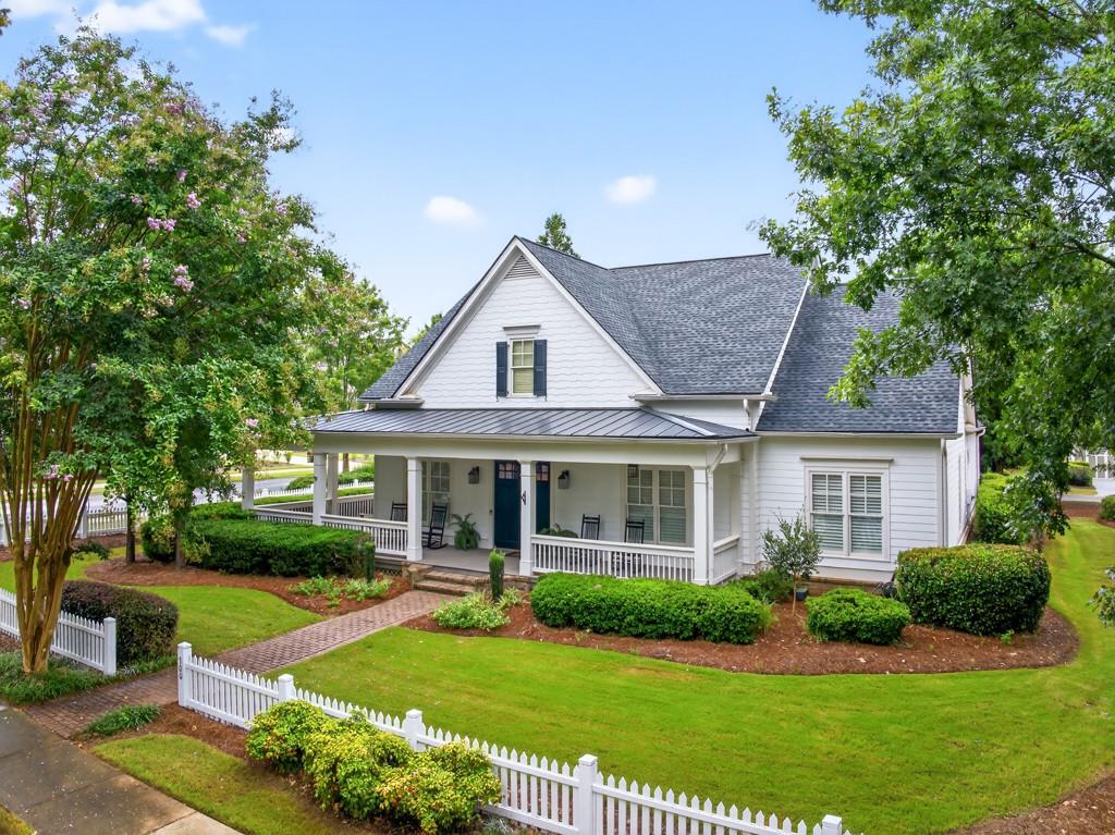 Welcome to this luxuriously upgraded 5-bedroom, 4-bathroom home in the highly sought-after Georgia Club, a gated golf course community known for its Southern charm and resort-style amenities. Situated on a premium corner lot, this beautifully maintained home features a white picket fence, a charming wraparound front porch, and a rear-entry garage, all adding to its curb appeal. Inside, enjoy new flooring, fresh interior and exterior paint, and thoughtful architectural details throughout. The spacious living room features a coffered ceiling, creating a sophisticated and inviting space for gatherings. The kitchen is accented with brick details, blending rustic warmth with modern utility. Perfect for remote work or study, the private office includes custom-built-in shelving. The oversized primary suite is a true retreat, featuring two large custom walk-in closets and a spa-inspired en suite bathroom with a large walk-in shower, double vanities, and elegant finishes. Enjoy year-round efficiency with a solar energy system and keep your landscaping lush with the automated sprinkler system. Located in The Georgia Club, residents have access to world-class amenities: golf, pools, tennis courts, clubhouse, fitness center, and walking trails. This home offers a rare combination of classic Southern charm and modern luxury in one of Georgia's most desirable communities.