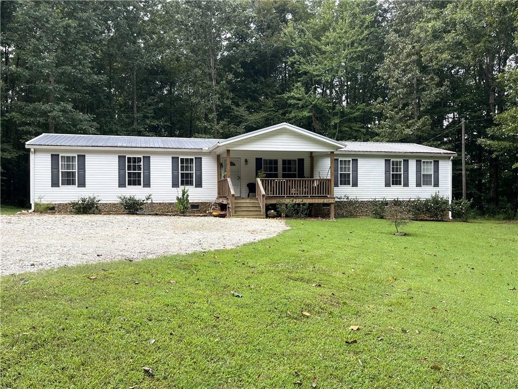 This attractive 4-bedroom mobile home sits on a sprawling 4.20-acre lot, offering privacy and room to breathe. Enjoy the tranquility of country living with the convenience of modern living. Recent upgrades include water heater, HVAC system, faucets, dryer and toilets ensuring peace of mind and energy efficiency.
Step inside to the living room. The large kitchen, a central hub for family and friends, features ample counter space, storage and modern appliances perfect for entertaining or daily meal prep. A spacious island provides a convenient breakfast bar or additional prep space. The home offers plenty of flexible living space with both a dedicated living room and a den. The split bedroom plan provides privacy and comfort, ideal for families or those who enjoy hosting guests. The expansive 4-acre property is a wonderful opportunity to experience comfortable and private living. The outdoor building is unique and can be utilized in many different ways. Don't miss out on owning this one-of-a-kind property.
