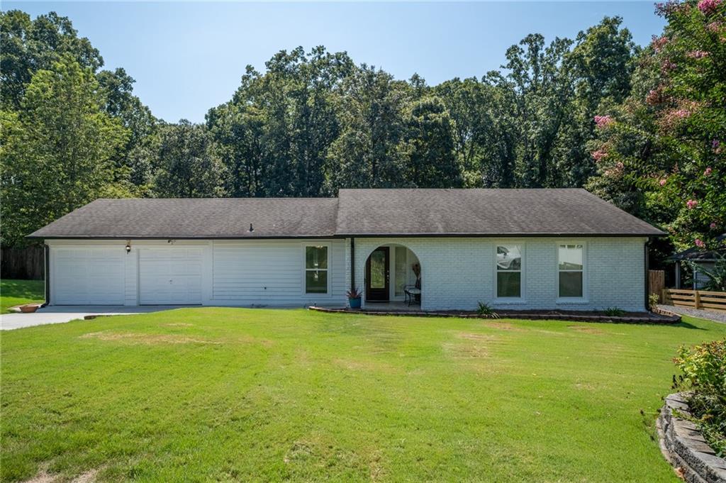 Spacious Ranch with Outdoor Living --
Step into your own private retreat with this inviting 3-bedroom, 2-bath ranch on a spacious 0.43-acre lot. The fully fenced backyard is designed for effortless outdoor living, featuring a generous patio for dining or gatherings, a raised deck for relaxed evenings, and wide stretches of green space surrounded by mature trees for added privacy. Inside, you’ll find approximately 1,305 square feet of updated living space. The light-filled living room showcases hardwood floors and a cozy fireplace, while the kitchen pairs granite countertops with plenty of cabinetry. Fresh paint, new bedroom flooring, and updated windows enhance this home with a move-in-ready feel. Major updates —including the roof, HVAC, driveway, patio, and deck—all completed within the last 7–9 years, provide lasting value and peace of mind. A two-car garage with fresh paint, new door motors, and a utility workshop closet adds even more functionality, along with the convenience of two driveways. Just minutes from Highway 316 and the Mall of Georgia, this home blends comfort, updates, and standout outdoor space in a location that keeps everything within easy reach.