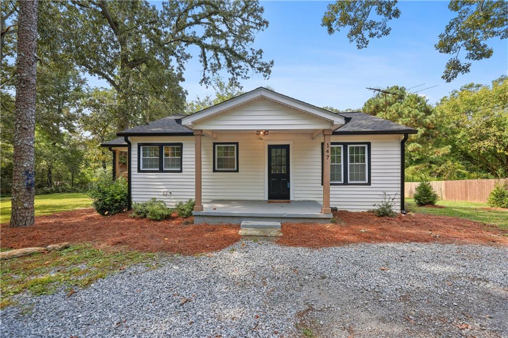 Welcome to this fully remodeled gem, thoughtfully updated in 2022 with a new roof, HVAC, windows, plumbing, and more, offering peace of mind and modern comfort for years to come. Step inside to an open-concept layout that seamlessly connects the kitchen, dining, and living areas. The stylish kitchen features white shaker cabinets, quartz countertops, and stainless steel appliances, while a convenient laundry closet sits just off the kitchen for everyday ease. The updated bathroom includes a sleek modern vanity and a tub with tile surround. Throughout the home, you'll find low-maintenance LVP flooring, updated lighting, and tasteful finishes that elevate the entire space. A smart split-bedroom layout offers added privacy, ideal for roommates or guests. Outside, relax on the charming front and side porches or take advantage of the spacious, level backyard perfect for creating your dream outdoor retreat. The lot extends beyond the grassy area, providing ample space to expand if desired. Centrally located between Atlanta and popular North Georgia (approximately 40 miles to either), this home is just 1 mile from I-575 and minutes to shopping, dining, and everyday conveniences. Furnishings negotiable. Added Bonus: Take advantage of the two neighboring homes also available for sale and create the ultimate family compound!