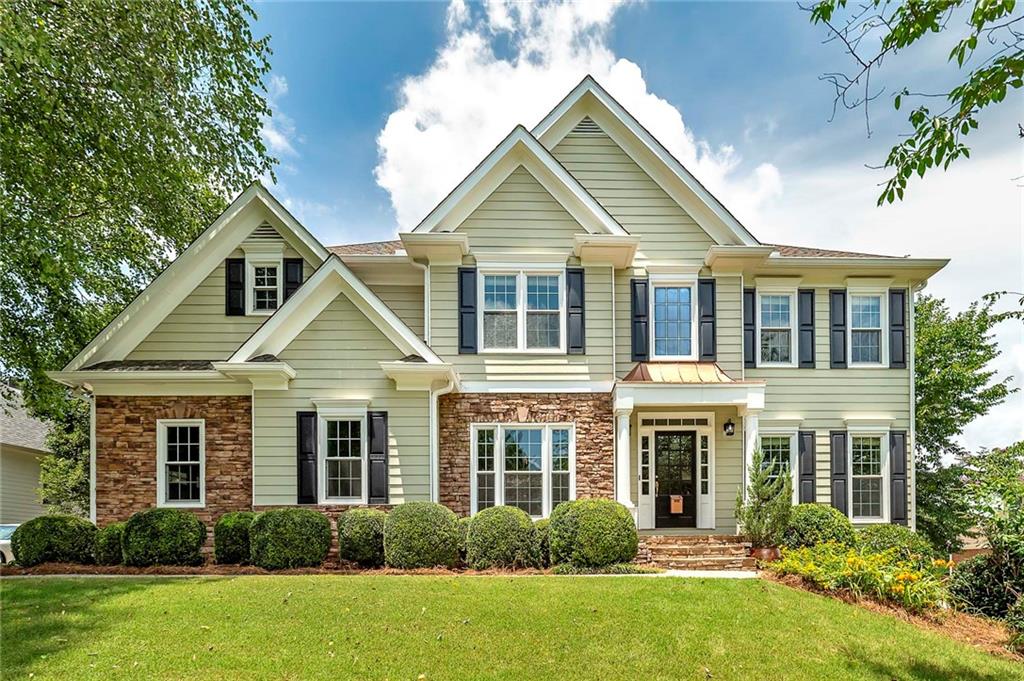 This stunning, spacious, light-filled beauty is situated on a landscaped, private lot located in Prestigious South Forsyth. This large, luxurious home was designed for family and entertaining. The fine architectural features and finishes accentuate the ideal floor plan for family and guests. Step into the 2-story light-filled foyer onto lustrous hardwood floors. To your left is a formal dining room perfect for hosting elegant dinners for 12 or more guests. To your right are picturesque French Doors opening into a home office with built-in bookcases. Directly in front of you is a sweeping two-directional staircase to the 2nd floor. Past the staircase with wrought iron banisters is the large, open family room with a stone fireplace framed by a decorative mantle. Open to the family room, the well-equipped kitchen features both a breakfast bar and nook ideal for brunches or after-school snacks and homework. Main level guest bedroom offers privacy and comfort with a spacious closet and a full bath that is conveniently located off the kitchen. Upstairs and to the right are two bedrooms with walk-in closets and a full bath. Upstairs to the left is another bedroom with a walk-in closet, a laundry room, and a huge master suite. The master suite features a huge walk-in closet. The totally renovated master bath has a double vanity, designer soaking tub with a shower wand, and a separate glass-encased shower. The partially finished basement features even more space for various interests and entertainment, including a wet bar, recreation, workout room, a bedroom, and is stubbed-out for a bathroom waiting for your finishing touches. The rear exterior of this home offers a wood deck overlooking the decadent flagstone courtyard with a massive stone fireplace and planters. Host a barbecue by the fire in this inviting outdoor space. Your family will love the area, conveniently located near Recreation, Parks, and Cultural Services, where fun and community come together. The county offers an outstanding park system, highlighted by landmarks like Fowler Park and the scenic Big Creek Greenway with walking trails, playgrounds, sports fields, arboretums, and so much more.