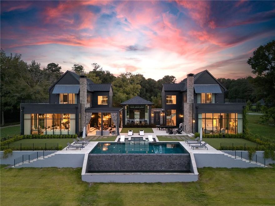 This stunning Milton estate combines privacy, modern farmhouse elegance and sweeping views in one extraordinary offering. The six-bedroom, six- and two-half-bathroom home-one of the last designed by Bill Harrison-and its state-of-the-art barn and greenhouse are tucked at the heart of 50  private acres, surrounded by fenced pastures, mature trees and two streams. The seven-stall barn and oversized arena features run-outs, a tack room, an office, a wash rack and a thoughtfully appointed break room. Suitable for a luxury wellness retreat, a private estate or a multi-use compound, this contemporary masterpiece offers 10,000+/- square feet of flexible living space. Inside, unrestricted living spaces unfold beneath 14-foot ceilings, where floor-to-ceiling aluminum-framed windows allow natural light to showcase high-end interior finishes. Two dramatic floating staircases double as architectural statements. The expansive grounds easily accommodate equestrian pursuits, formal gardens or private event spaces, with patios and balconies that immerse guests in the surrounding beauty. The PebbleTec infinity-edge pool with a sun ledge and spa provides a stunning focal point for those seeking bespoke entertaining spaces, and a full fitness and indoor spa suite caters to health-minded owners. Welcome to 14200 Hopewell Road located only 5 minutes from Historic Downtown Alpharetta!