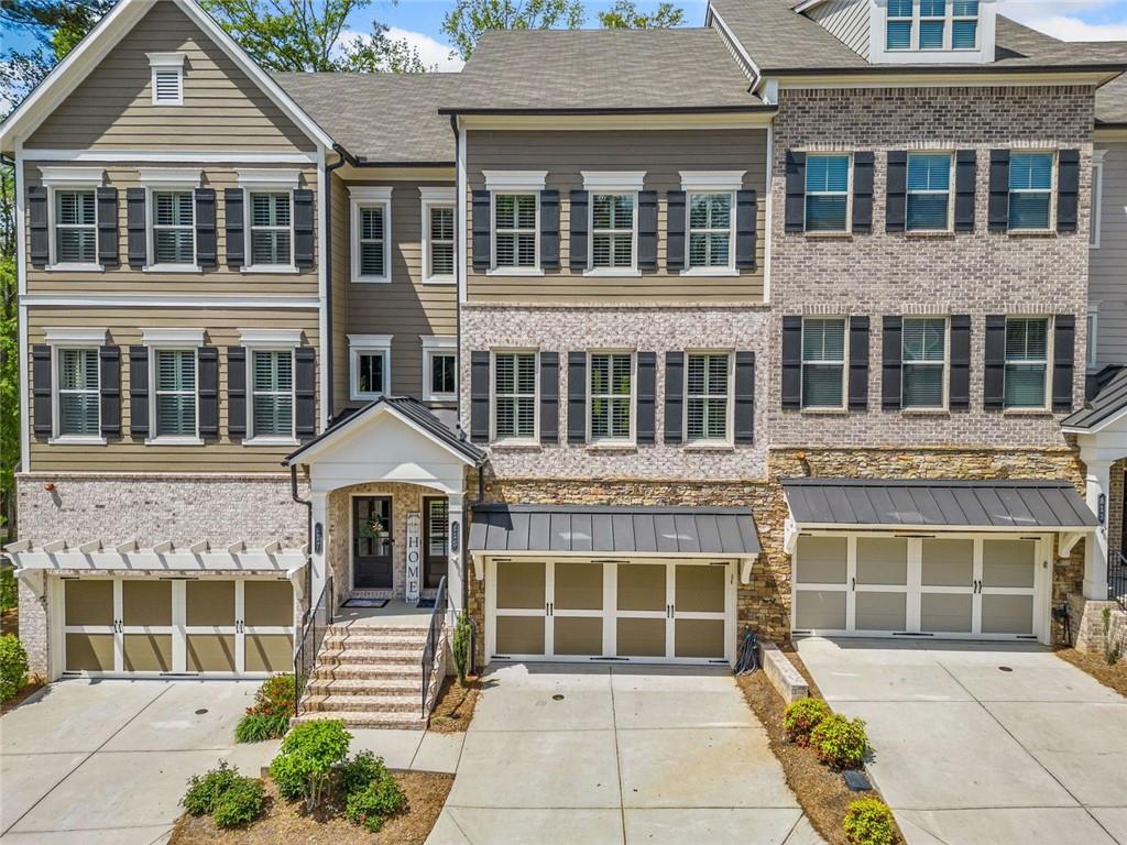 Welcome to one of Downtown Woodstock’s most coveted addresses, where location, lifestyle, and luxury converge. Nestled seconds from award-winning restaurants, boutique shopping, and vibrant local entertainment, this stunning three-story townhome offers the ultimate in city living. All in a part of town highlighted three seperate times by Money Magazine’s Best Places to Live! Situated next to the scenic Noonday Creek Trail and only half a mile from I-575, this home delivers unmatched accessibility with a serene suburban feel. Look inside to discover brand-new interior and exterior paint and a warm, inviting design anchored by a one-of-a-kind wood accent wall that leads you from the foyer up to the open-concept main living area. This supremely desired layout features dual primary suites one on the terrace level and one upstairs, perfect for multigenerational living or added privacy. Enjoy hardwood floors throughout, plantation shutters, and refined finishes in every room. The open concept kitchen boasts granite countertops, a large island with built-in storage, ample cabinet space, and a spacious pantry, plus a custom bar area that’s ideal for entertaining. Upstairs, the primary suite offers a spa-like retreat with an oversized tiled shower, bench seating, dual vanity, and a custom closet system designed to impress. Additional features include an epoxy-coated garage floor, overhead garage storage, security system, and more all wrapped into a low-maintenance, lock-and-leave lifestyle in one of Georgia’s most desirable communities. This is more than a home, it’s a lifestyle. Come experience Downtown Woodstock at its finest