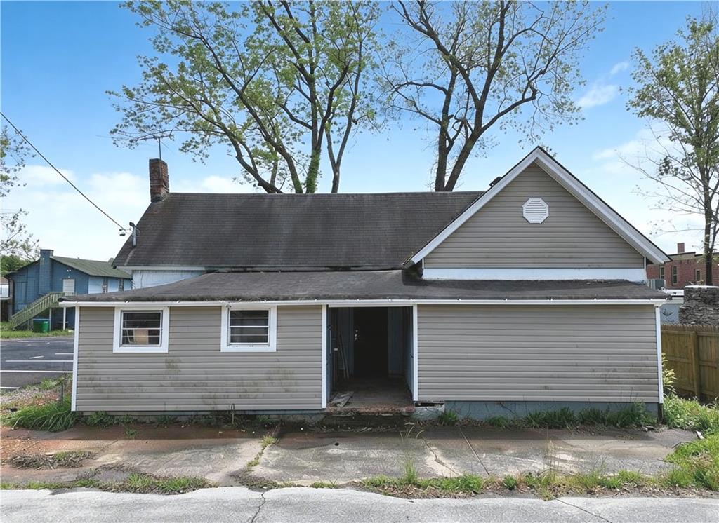 View of front facade with a chimney and a shingled roof