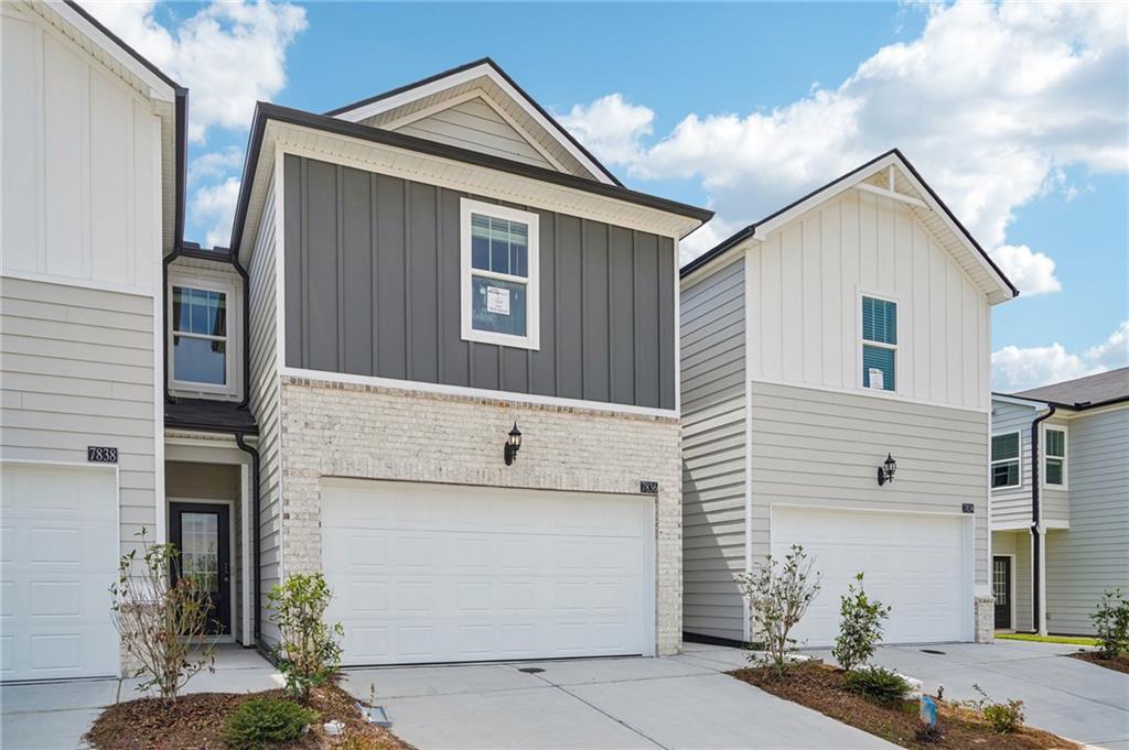 View of front of property featuring an attached garage, board and batten siding, concrete driveway, and brick siding