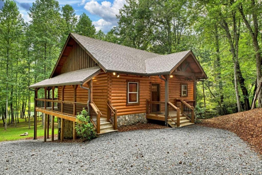 Nestled along the pristine shoreline of the Toccoa River, this true log home blends timeless craftsmanship with effortless mountain living. Built with Satterwhite Logs and accented by Tennessee fieldstone, the residence has been meticulously maintained and showcases over 100 feet of direct river frontage. Set on gentle, usable acreage with a rare flat backyard, the property offers an ideal riverside lifestyle. A small creek winds through the land, flowing gracefully into the Toccoa-perfect for nature lovers and those seeking a serene retreat. Inside, warm red oak hardwood floors and a warm-rustic aesthetic create a welcoming atmosphere. The kitchen pairs bird-pecked hickory cabinetry with stone countertops for a touch of natural refinement. The open-concept design extends to a spacious great room and continues to the wraparound deck, where lush backyard and river views set the backdrop for relaxation. The terrace level expands the living space with a full den and a walk-out patio, ideal for entertaining or quiet evenings by the water. With fiber internet service (300/300 mb) already in place, the home is as connected as it is peaceful. Offered fully furnished, less than ten minutes to Downtown Blue Ridge and Lake Blue Ridge, this riverside cabin is ready for immediate enjoyment-whether as a full-time residence, weekend escape, or short-term rental opportunity.