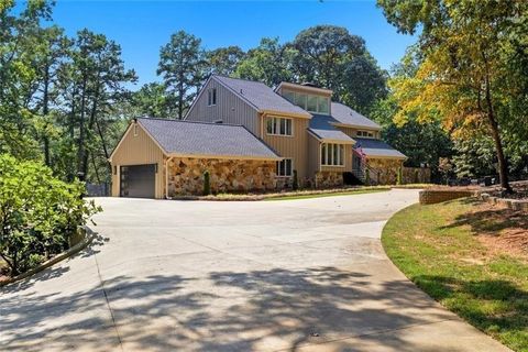 Modern single-family residence at 3518 Lake Breeze Lane, showcasing a large driveway, stone and wood exterior, surrounded by lush greenery in Gainesville, GA, emphasizing the appeal of lakefront living near Lake Lanier.