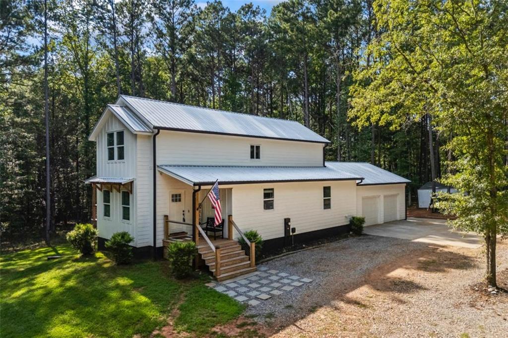 Tucked away on 2.7 wooded acres yet just minutes from Highway 78, this charming home offers easy access to Monroe, Athens, and Bethlehem while providing the seclusion and space you've been looking for. Downtown Monroe is less than 3 miles away and features locally owned shops, seasonal festivals, outdoor concerts, and excellent dining. A welcoming front porch with a stained wood ceiling opens into a light-filled floor plan with stunning white oak floors throughout the main level. The living room flows seamlessly into the dining area and kitchen, designed for both everyday living and entertaining. The kitchen serves as the heart of the home with quartz countertops, custom cabinetry, floating shelves, stainless steel appliances, and a large island. Also on the main level are a half bath and a spacious mudroom/laundry room with built-in cabinetry and access to the oversized two-car garage. The owner's suite is complete with a walk-in closet with built-ins and an en-suite bath featuring double vanities and a tiled shower. Upstairs, you'll find a generous loft area or flex space, along with two oversized bedrooms, each with its own private bathroom with tiled floors and tiled tub/shower combo. The full finished basement expands the home with a kitchenette, a large living/flex area with a generous sized storage closet, a bedroom, and a full bath with a tiled shower. Step outside and enjoy the peace and privacy of your wooded surroundings from the covered deck or extended patio. With its thoughtful design, high-end finishes, and an unbeatable location close to shopping, dining, and entertainment, this home offers the best of both worlds, peaceful living with quick access to everything.