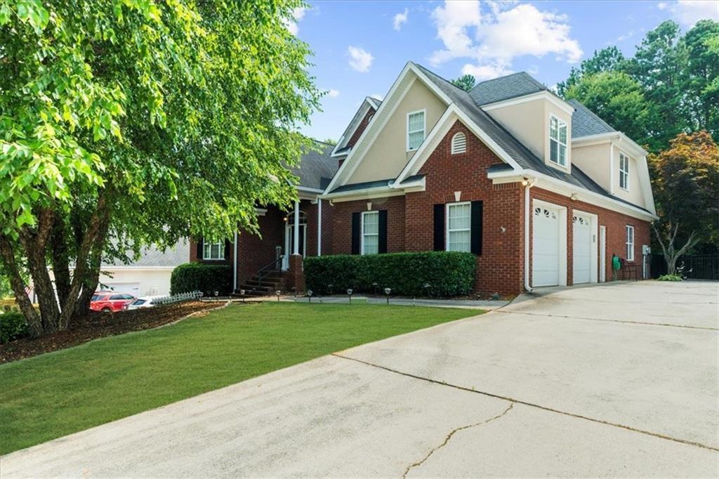 Brick and stucco exterior featuring dormer windows and a two-car garage