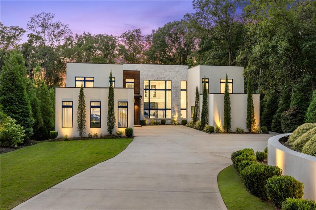 Gated, private, and perfectly positioned on over an acre in the heart of Buckhead, this modern estate—completed in May 2021 by Bella Fine Homes—pairs elevated architecture with resort-caliber outdoor living. Brazilian Ipe wood details married with a marble facade, expansive glass walls, and black glass garage doors create a striking first impression.
Upon entry a soaring 20-foot ceiling crowns the light-filled great room, anchored by a Chihuly-inspired hand-blown glass chandelier and a sleek linear fireplace. 16-foot bifold doors completely pocket open dissolving the boundary between indoors and out, opening to a covered lanai with flush-mounted patio heaters, a linear fire table, and a fully equipped outdoor kitchen. From here, the walk-out main-level saltwater pool with
twin waterfall features topped with fire bowls and 12-person hot tub takes center stage, framed by an astroturf backyard, hidden outdoor pool bath, and fire pit lounge.
The chef’s kitchen is both a design statement and a culinary command center—featuring a massive quartzite island with a 3-inch waterfall edge, full-height slab backsplash, custom flat-panel cabinetry, and a suite of Smeg and Miele appliances including dual wall ovens, steam oven, built-in espresso machine, pot filler, and Miele side-by-side refrigeration. A walk-in pantry, scullery/laundry room, and dry bar with wine fridge add
functional elegance.
Two primary suites—one on the main level with private patio access—offer the utmost in relaxation with custom closets, spa-like baths with His + Hers toilets and bidet, heated floors, floating vanities, and quartz countertops. The downstairs Primary has its own office attached opening to the backyard. All bedrooms are en suite, joined by upstairs reading lounge, and abundant storage.
The full finished terrace level extends the entertainment programming downstairs with a media room and 12-foot screen, wet bar, gym, large gas fireplace, and a powder room with direct pool access.
Smart-home infrastructure includes security cameras, in-ceiling audio/speakers, wholehome lighting control, wiring for automated shades, in-wall iPad controls, colorchanging LED accent lighting, central vacuum, and Honeywell security. Additional amenities include a 3-car garage with EV charging port, whole-house generator, and professionally landscaped grounds with irrigation.
A true modern architectural statement, offering the rare combination of high design, advanced technology, and resort-style amenities in one of Atlanta’s most desirable locations.