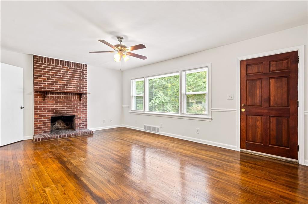 Unfurnished living room featuring a ceiling fan, hardwood / wood-style flooring, and a brick fireplace