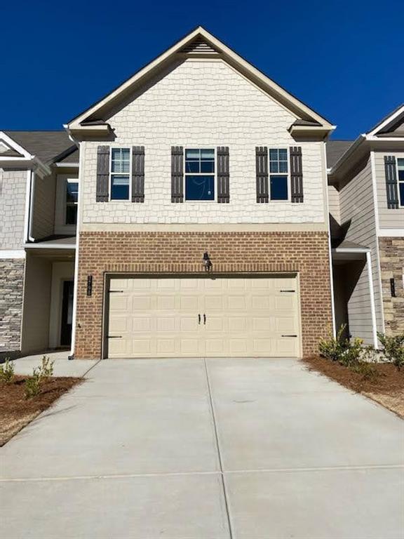 Two-story residential exterior featuring a light-colored garage door with decorative hardware
