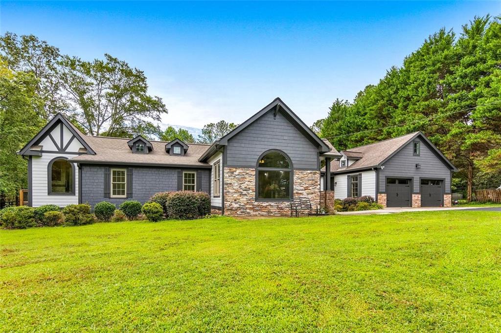 Discover the perfect private retreat in the heart of Woodstock! Nestled on 1.55 acres behind a private gated entrance, this inviting 3 bed / 2.5 bath craftsman ranch home combines timeless design with thoughtful updates. Inside, a sun-filled layout welcomes you with a formal sitting room, dry bar, and dining area. The home features LVP flooring and soaring 10–12 ft ceilings throughout. The elegant kitchen is complete with granite countertops and stainless steel appliances, including an LG electric range and refrigerator. The fireside living room offers a cozy retreat, while the primary suite impresses with its own electric fireplace and spa-like bath featuring a granite double vanity, jetted tub, and separate shower. Two additional bedrooms share a full hall bath, and a convenient hallway laundry closet comes complete with a washer and dryer. Recent upgrades include a roof within the last 5 years, a new deck with cedar-top railings & pine bottom wood, gutter guards, vapor barrier & fans in the crawlspace, and a detached two-car garage connected by a breezeway. With low utility bills, this home offers both comfort and efficiency. Outdoors, enjoy a fenced yard, well water for gardening, and a variety of fruit trees including cherry, pear, apple, peach, plum, and fig, along with Scuppernong grapevines and muscadine. Four storage sheds and a chicken coop complete the property, delivering a true homestead feel with modern conveniences.