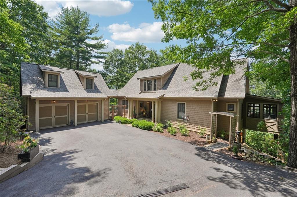 Stunning Chestnut Hill Plan with Panoramic Mountain Views in Big Canoe
Step into timeless Southern charm with this beautifully crafted Chestnut Hill home, perfectly positioned to capture sweeping mountain views through walls of windows. Located in the prestigious gated community of Big Canoe, this residence blends architectural elegance with thoughtful functionality.
The spacious main-level family room features a soaring stacked stone fireplace and custom built-ins, creating a warm, inviting gathering space. It flows seamlessly into the gourmet kitchen, complete with high-end finishes, generous workspace, and a well-planned layout ideal for both cooking and entertaining. The adjoining dining area opens to an Eze-Breeze screened porch and a side deck, perfect spots to soak in the surrounding natural beauty year-round.
The main level owner's suite includes a serene sitting room and a luxurious, spa-inspired bath. Upstairs, you'll find two additional bedroom suites and a cozy loft, offering privacy and comfort for guests or family.
The terrace level boasts a second fireside family room that opens onto a large deck and screened porch. An additional guest bedroom with full bath ensures plenty of space for visitors. Also on the terrace level: an impressive, fully equipped woodworking workshop with a half bath and ample storage.
Additional Features:
Detached garage with finished, climate-controlled bonus space above, ideal for an office, studio, or man cave
Newly replaced roof for peace of mind
Main-level Trex decking for low-maintenance outdoor living
Home generator
Central Vac
Lightening protection
AHC home warranty
Exceptional craftsmanship and detail throughout
This exceptional home offers a rare combination of craftsmanship, comfort, and breathtaking views in one of North Georgia's most desirable mountain communities.