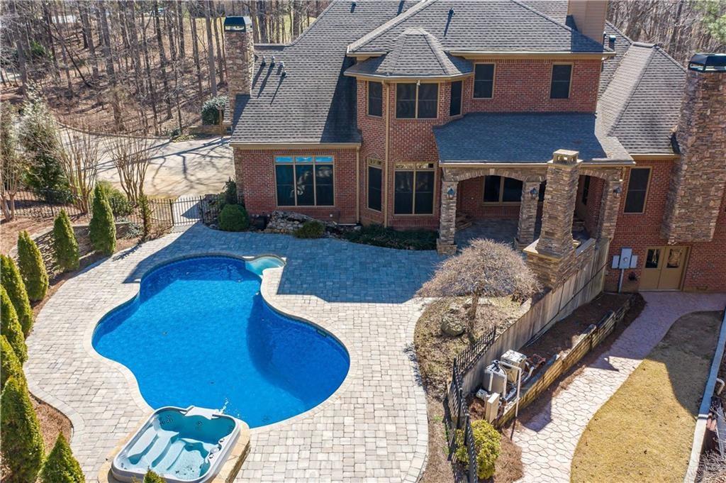 Welcome to this custom executive estate—private yet convenient. Built with 4-side brick and stacked stone, it features a chef’s kitchen with Sub-Zero fridge, 6-burner gas range, island, and walk-in pantry. The family room has coffered ceilings and a stacked stone fireplace. The master suite offers a spa-like bath, fireplace, private access to the outdoor oasis with pool, hot tub, and cabana. A 3 car epoxy-floored garage, dual laundry rooms, and expansive indoor/outdoor living complete the picture. Inside, enjoy a keeping room with ventless fireplace, open-concept layout, and dining area with stacked stone columns. The master bath boasts dual vanities, steam shower, soaking tub, and backlit mirrors. His and Hers closets include a full laundry and dressing area. Upstairs are four en-suite bedrooms, a large bonus room, and second laundry. The finished basement includes a home theater with 100" screen, Sonos Hi-Fi, copper coffered ceiling, gym, secondary kitchen, gaming area, workshop, safe room, and walk-out deck. Outdoors, entertain with a poolside cabana, grilling station, and private hiking trails. This estate blends luxury, comfort, and nature for a truly elevated lifestyle.