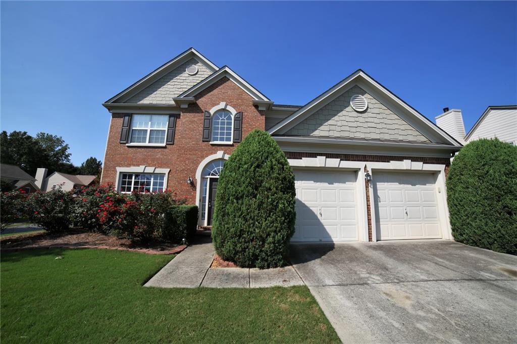 View of front facade with concrete driveway, an attached garage, a front lawn, and brick siding