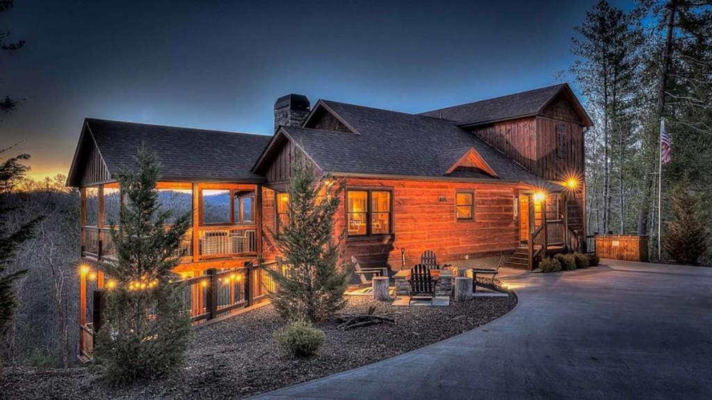 Perched on a private ridge with breathtaking long-range views stretching across three states, Painted Sunset Lodge combines rustic charm with modern luxury. With all-paved access just minutes from Downtown Blue Ridge, this remarkable four-bedroom, three full bath, and two powder room retreat is designed for both relaxation and entertaining. The main level offers an airy open-concept living area, anchored by a stone fireplace and framed by expansive windows that showcase dramatic mountain sunsets. A gourmet kitchen with generous counter space and premium finishes flows seamlessly into the dining and living areas, while sliding doors open to a covered deck complete with fireplace, dining space, and lounge seating-all overlooking sweeping vistas. Three private king suites provide comfort and privacy, each with a well-appointed bath, while a fourth bunk room is ideal for family or guests. Across two spacious levels, multiple gathering spaces include a second living room and a terrace-level den with its own fireplace, full wet bar, and game area. Distinctive finishes-warm wood interiors, soaring ceilings, and thoughtful details-enhance the home's mountain lodge character. Outdoor living is equally compelling, with multiple decks, a hot tub, a swinging bed, and an easy-access fire pit perfect for evenings under the stars. Whether as a full-time residence, vacation retreat, or investment property, Painted Sunset Lodge offers unmatched views, rustic elegance, and convenient access to the best of North Georgia.