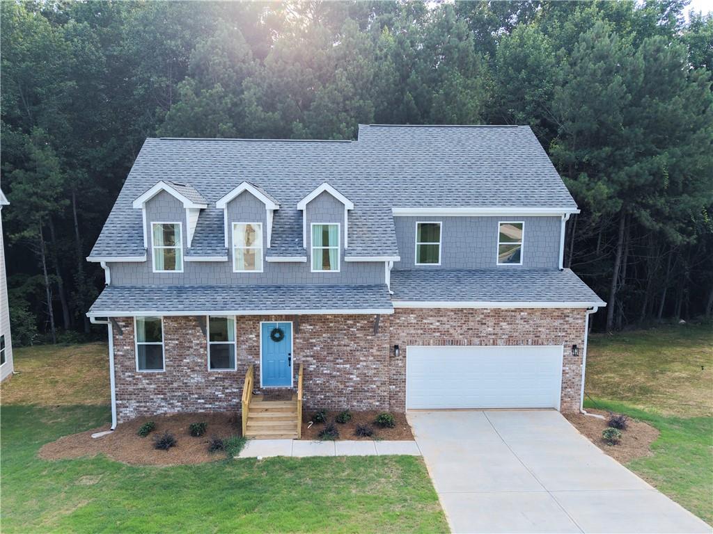 Two-story residence featuring a brick and gray siding exterior, a light blue entry door, an attached two-car garage, and a newly installed shingle roof