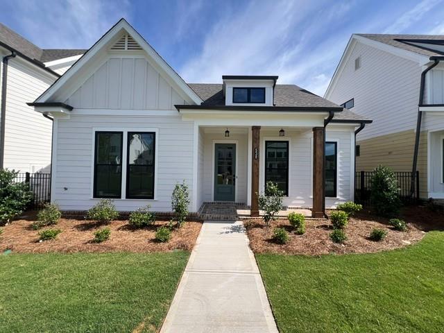 Contemporary white exterior featuring black-framed windows, a covered front porch with wood-finish columns, a dormer window, and a light-colored entry door