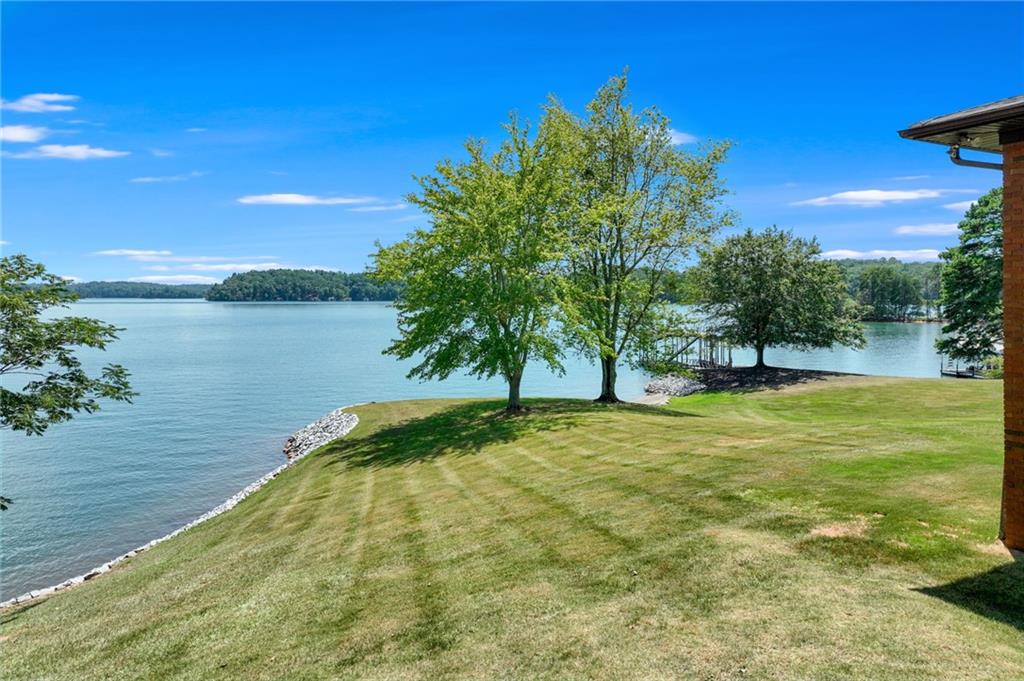 This is a rare opportunity unlike anything else on the market. With approximately 465 feet of lake frontage across three expansive lots, you'll enjoy panoramic views for miles. The value lies in the land—the existing structure is not being valued. Endless potential to build your dream lakefront retreat. A mowing permit is in place, allowing grass to the water’s edge across much of the property. Brand new permitted dock with slip. Features include a circle driveway, abundant road frontage, and a prime location close to Gainesville, shopping, dining, and convenient access to GA 400. This is a one-of-a-kind opportunity for lake living at its best!