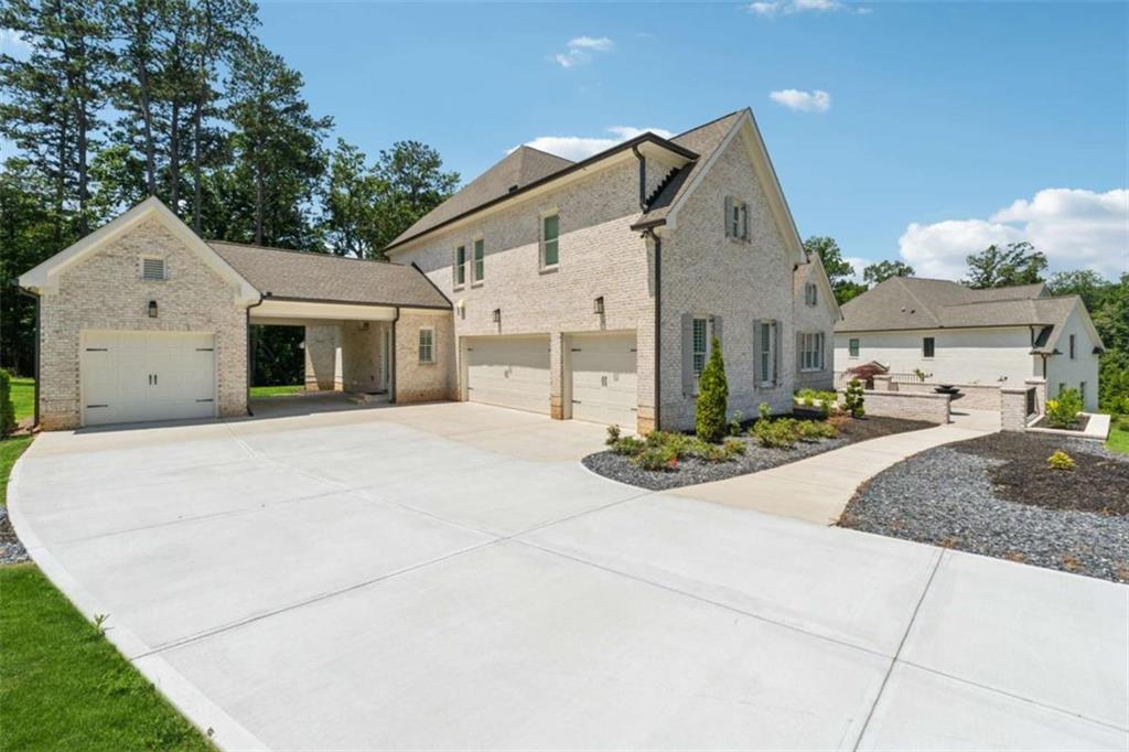 Nestled on two private acres in the coveted Breamridge community, this stunning four-sided brick estate invites you to experience the very best of Milton living-where timeless craftsmanship, luxurious finishes, and thoughtful design come together effortlessly. From the moment you arrive, the home's classic elegance makes an impression. A Porte-cochere connects the main home to the detached fourth-car garage, enhancing both the curb appeal and functionality of the residence. Whether you're hosting a grand gathering or returning home after a long day, this gracious entry sets the tone for what lies beyond. Inside, natural light floods the soaring two-story foyer, where warm white oak hardwood floors guide you through an open and airy layout. The main level offers a bright formal living room or home office, a generous dining room perfect for special occasions, and a luxurious primary suite with peaceful views of the backyard-ready for a future pool or enjoyed as-is. At the heart of the home, the chef's kitchen blends beauty and function. Outfitted with double ovens, a built-in refrigerator, a hidden walk-in pantry and a large island ideal for prep or casual dining, the kitchen flows effortlessly into both the main living room and a cozy keeping room-a perfect spot for morning coffee or evenings by the fire. Upstairs, four oversized secondary bedrooms each feature custom wood-shelved closets and private en-suite bathrooms, offering space and privacy for all. A large unfinished basement provides endless potential for future expansion or personalization. Step outside, and you'll find a true outdoor sanctuary. The covered patio extends to a fully equipped built-in kitchen with grill, refrigerator, sink, and pizza oven-ideal for hosting friends and family year-round. Two outdoor dining areas, a cozy fire pit, and lush landscaping complete the perfect setting for entertaining or quiet evenings at home.
